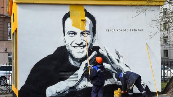 Das Bild zeigt ein Graffiti von Alexej Nawalny, wie es gerade übermalt wird