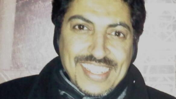 Porträtfoto von Abdulhadi Al-Khawaja, der eine Jacke und ein Schal trägt und die Kamera lächelt.