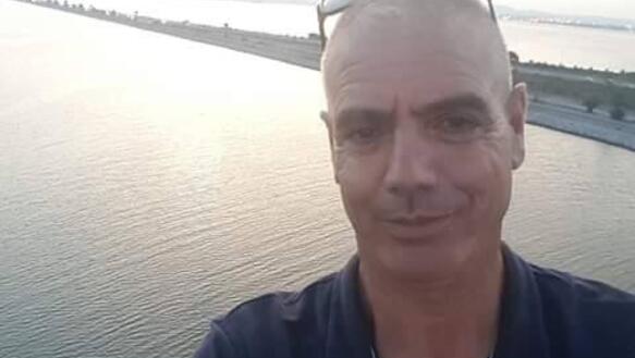 Porträtaufnahme von Slimane Bouhafs mit Gewässer im Hintergrund. Er trägt ein kurzärmeliges Hemd und lächelt leicht in die Kamera.