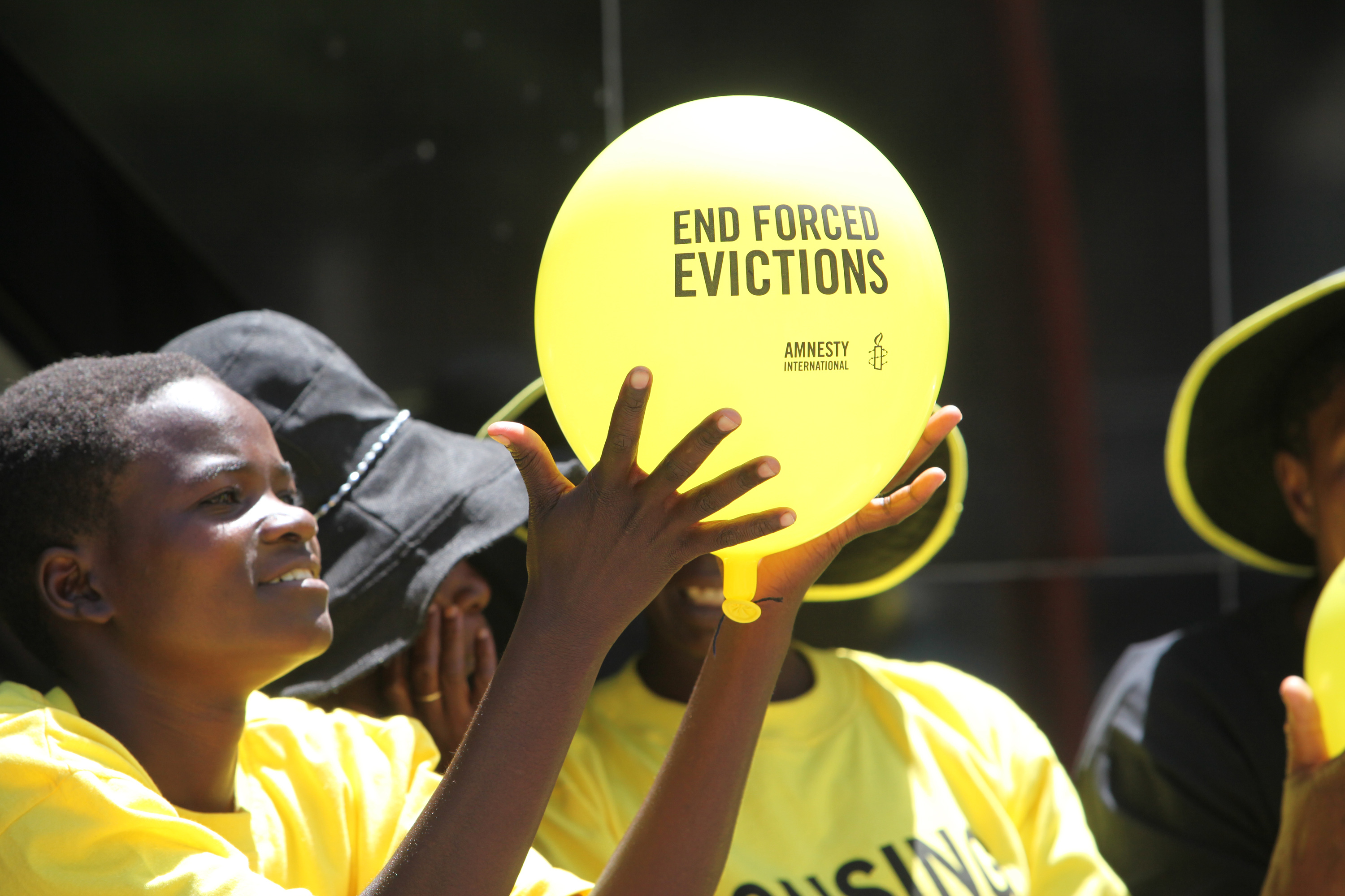 Junger Mensch hält Luftballon mit der Aufforderung "End forced evictions" in die Höhe