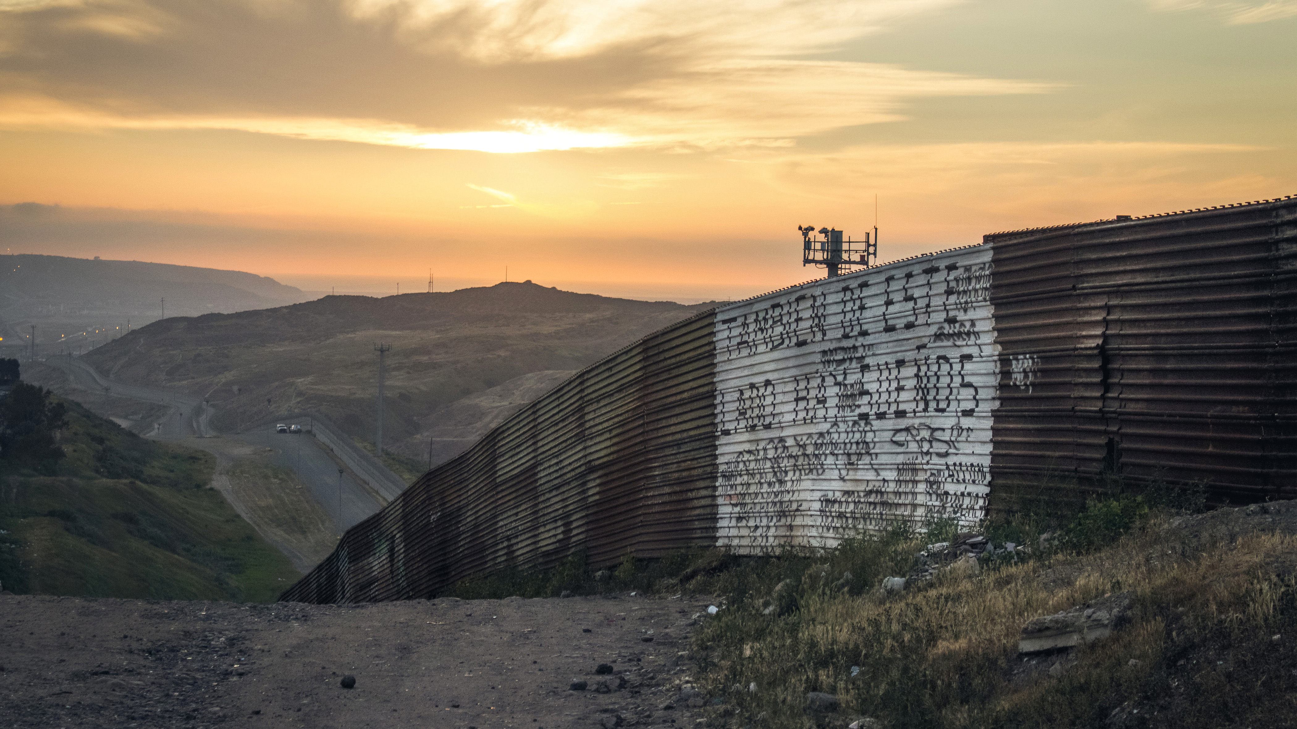 Ein langer Metallzaun zieht sich bis zum Horizont an der Grenze zwischen Mexiko und den USA