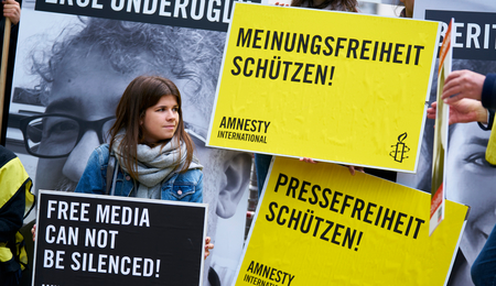 Junge Frau steht vor Plakaten zum Thema Meinungsfreiheit
