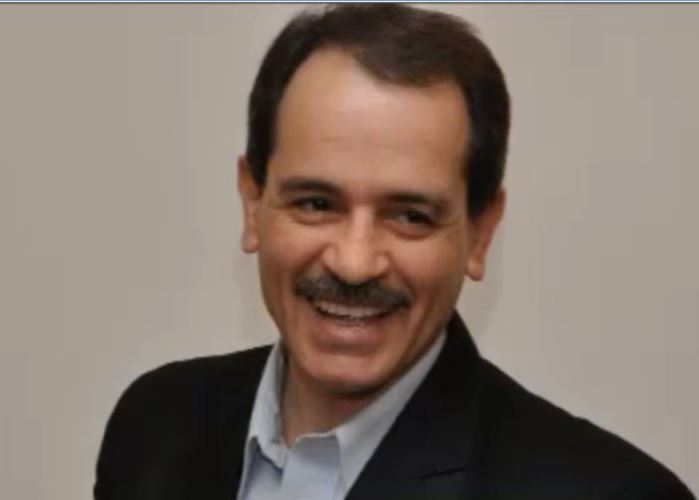 Foto von Mohammad Ali Taheri, auf dem er lächelt und ein Jacket trägt und rechts an der Kamera vorbei schaut.