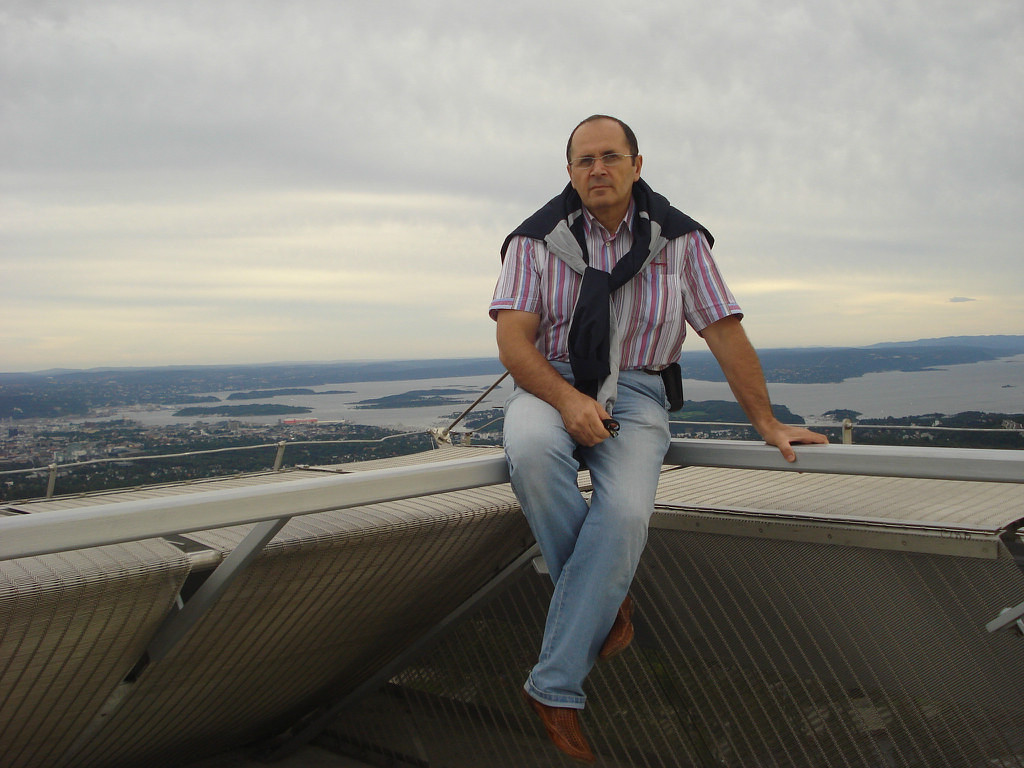 Oyub Titiev sitzt auf einem Geländer, hinter ihm eine Landschaft mit Seen