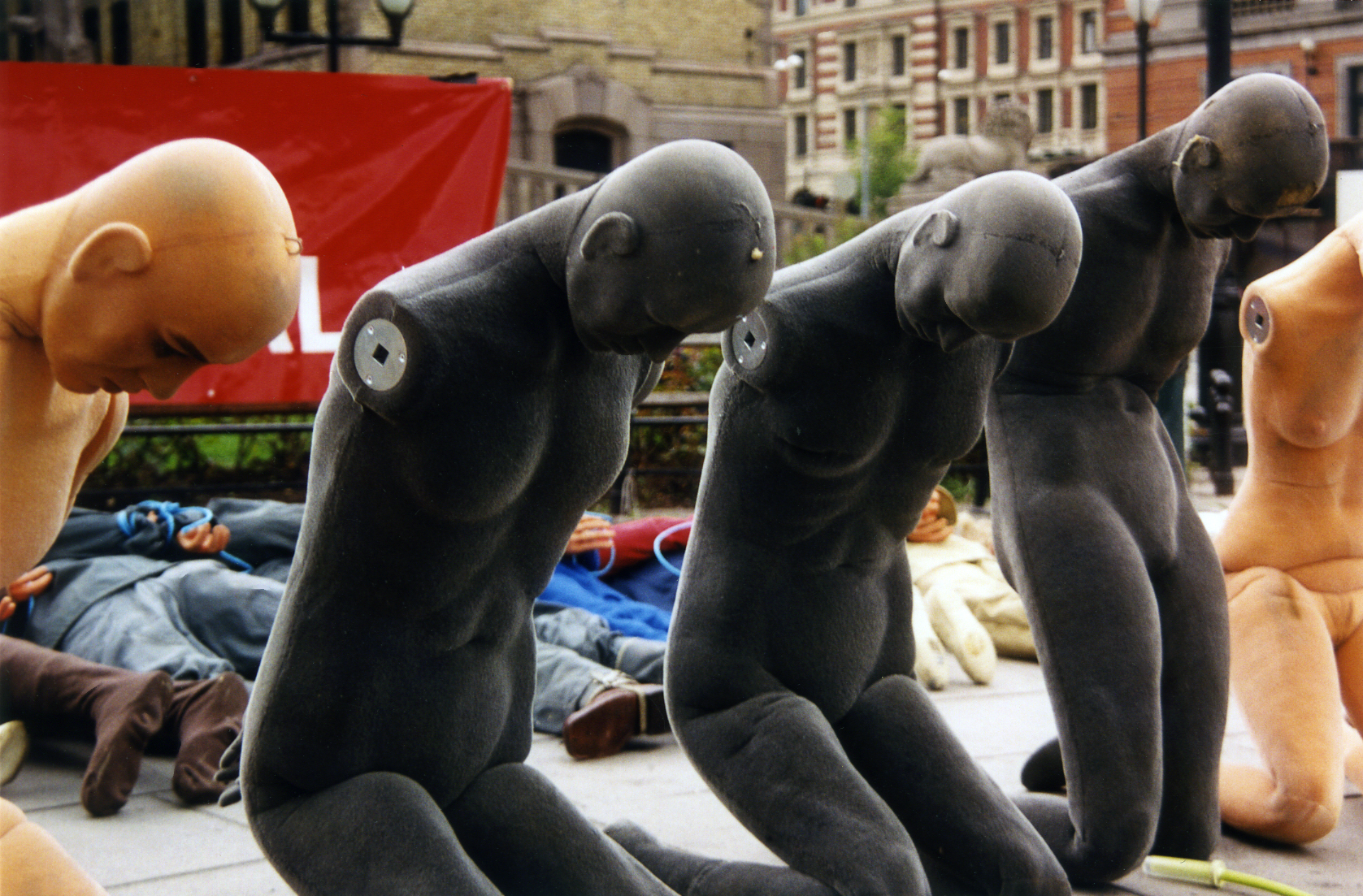 Dummy Puppen sind auf den Knien mit gesenktem Kopf auf einem öffentlichen Platz