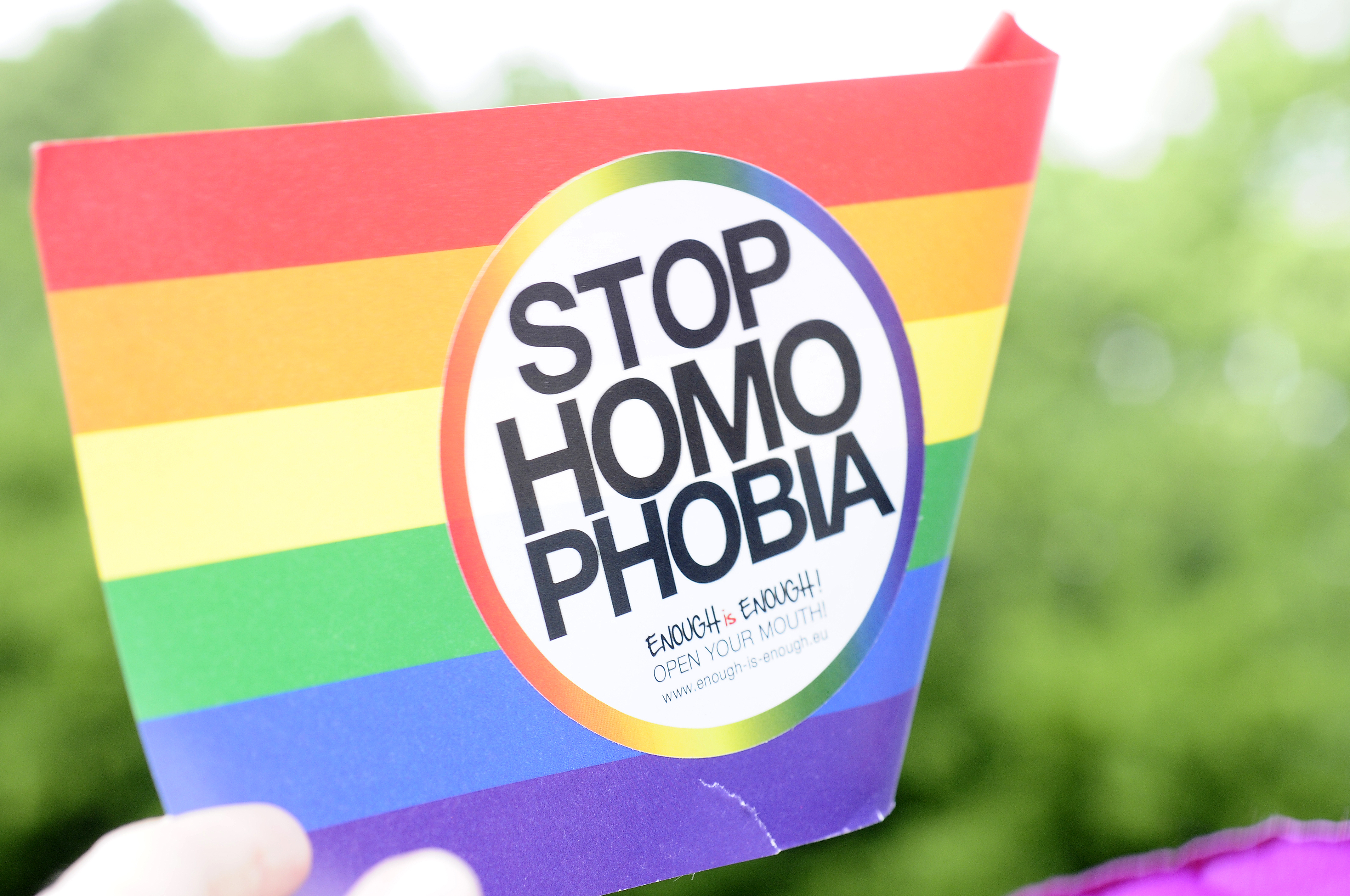Handfahne in Regenbogenfarben mit Aufschrift Stop Homophobia