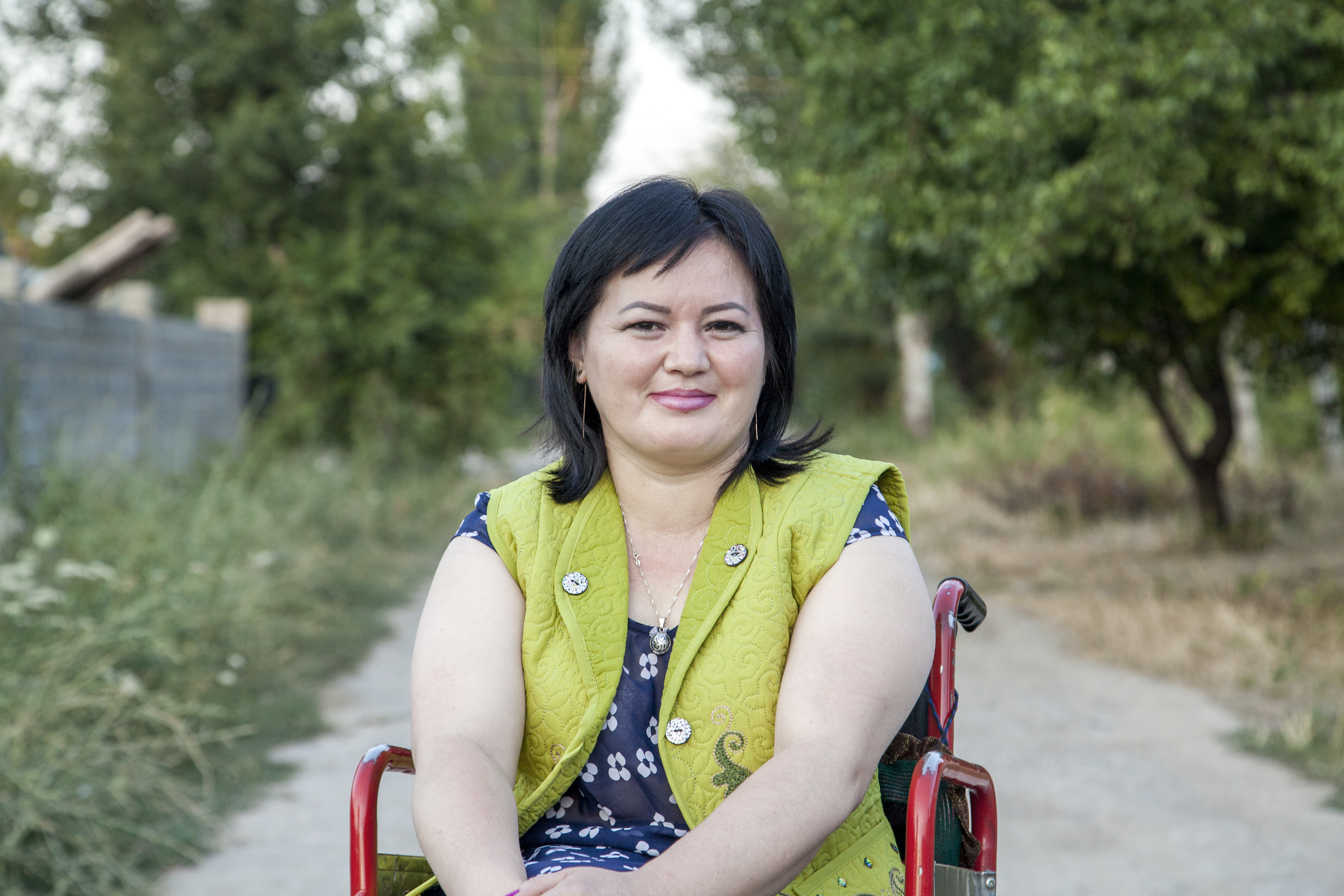 Porträtfoto von Gulzar Diushenova auf einem betonierten Weg zwischen Bäumen