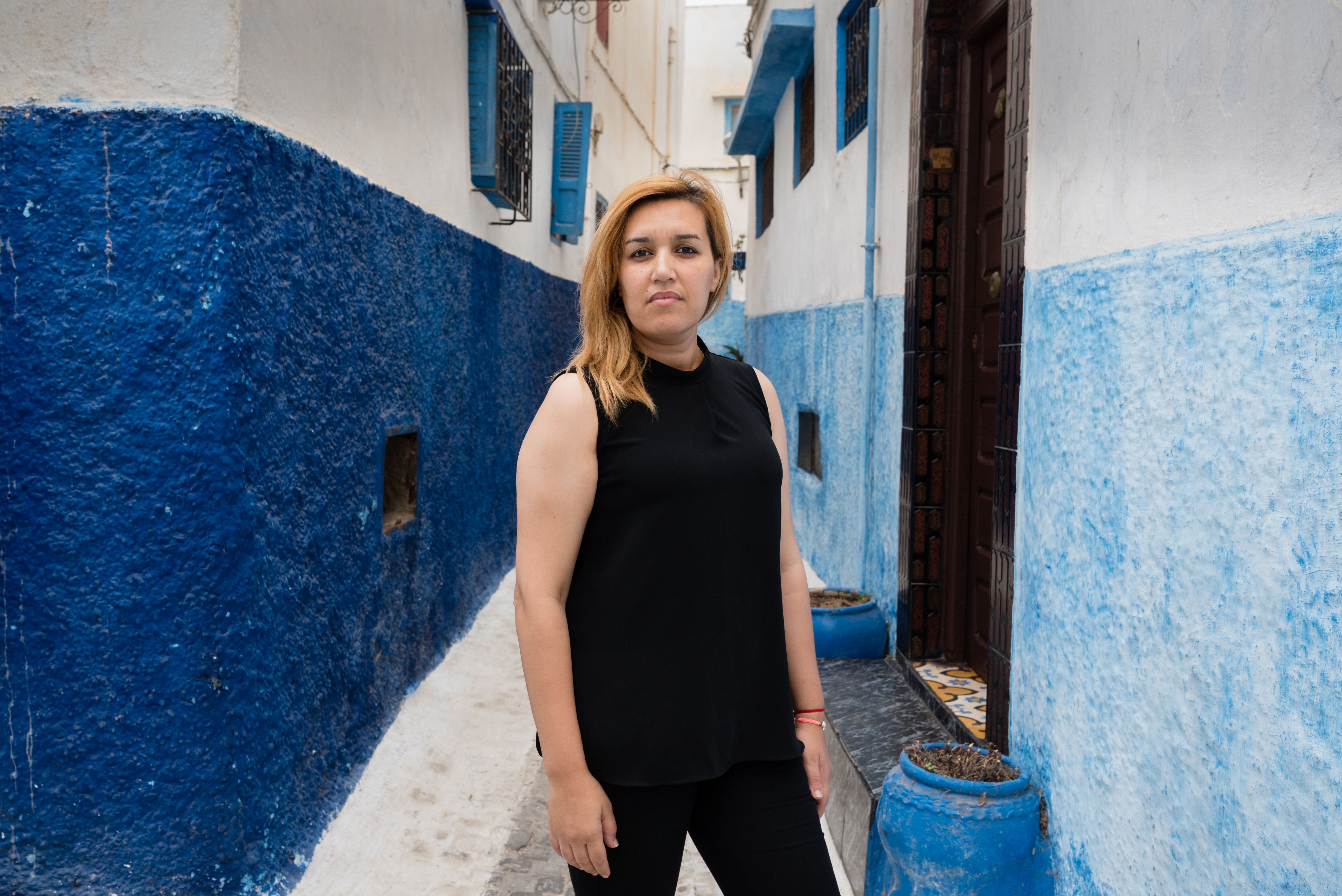 Porträtfoto von Nawal Benaissa zwischen blau-weiß gestrichenen Häusern