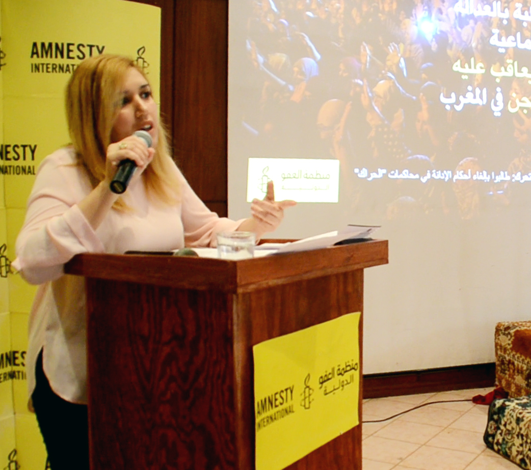 Nawal Benaissa an einem Rednerpult mit dem Logo von Amnesty International.