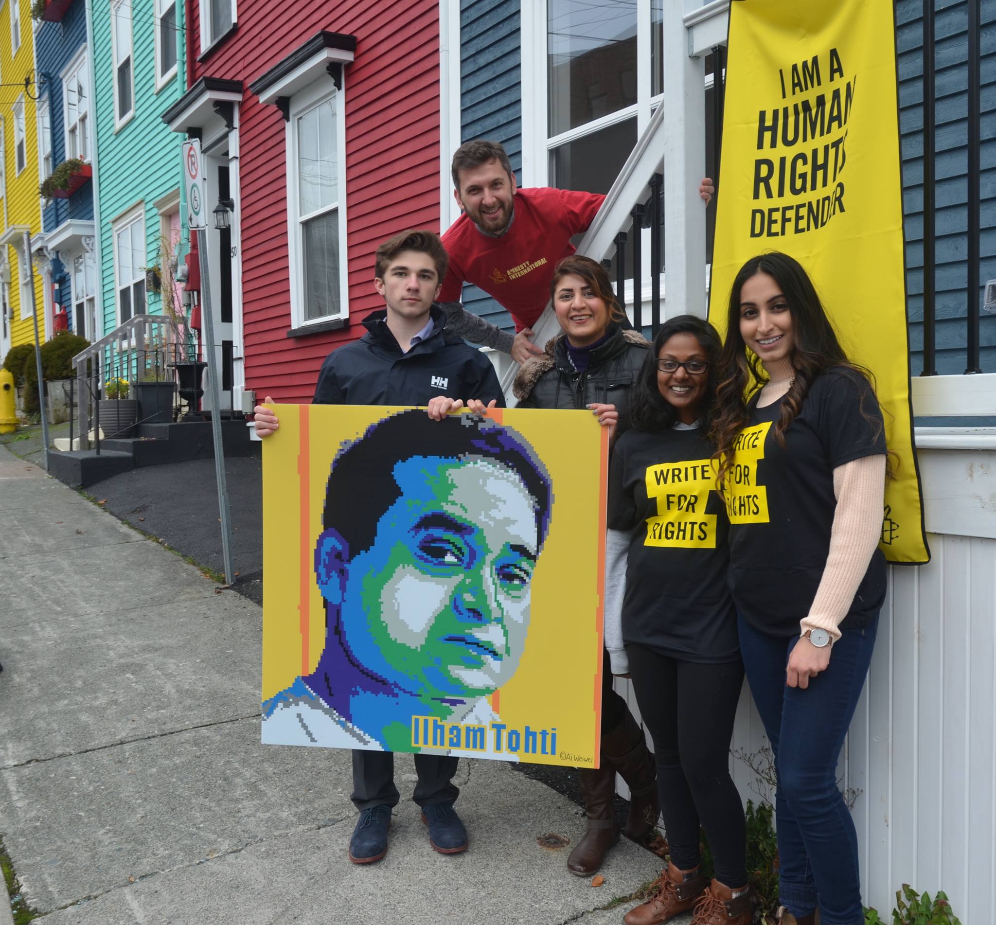 5 Jugendliche halten ein Plakat mit dem Bild von Ilham Tohti und ein Amnesty-Transparent in die Kamera.