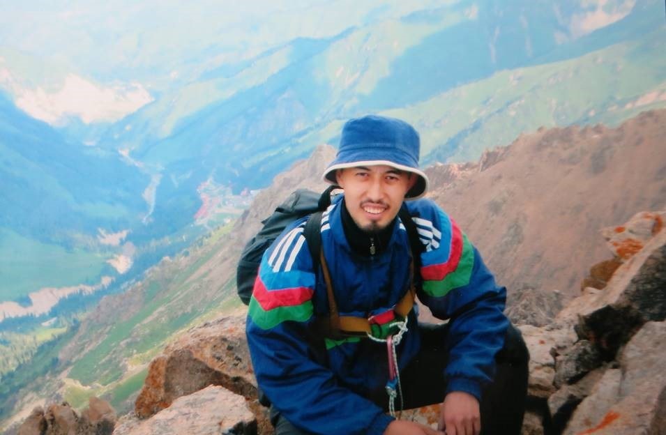 Junger Mann beim Bergsteigen, lacht in die Kamera