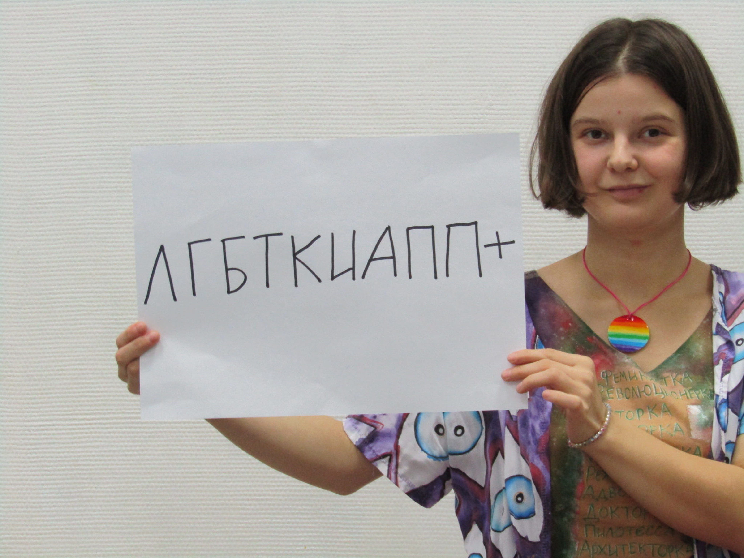 Eine junge Frau hält einen Zettel mit russischer Schrift in die Kamera.