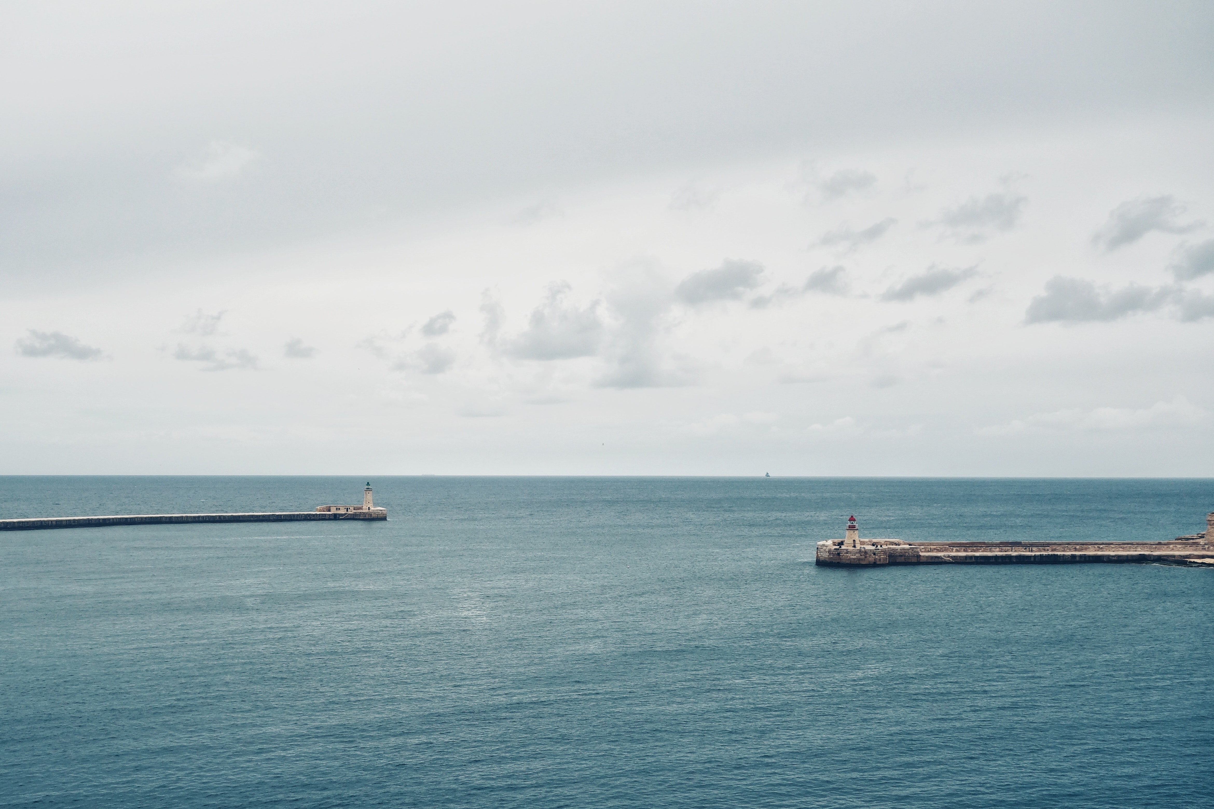 Foto vom Meer mit grauem Himmel, links und rechts historische Türmchen und Mauern eines Hafenbeckens