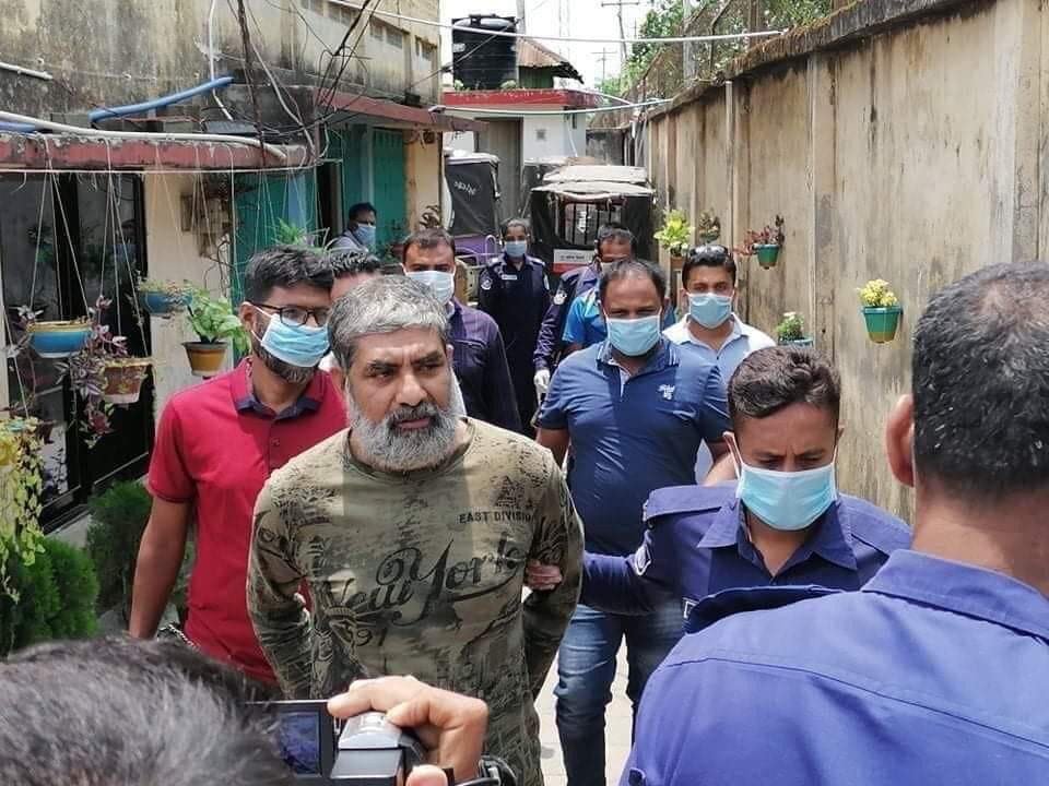 Ein Mann wird von anderen Männern mit Mundschutz durch eine Gasse geführt