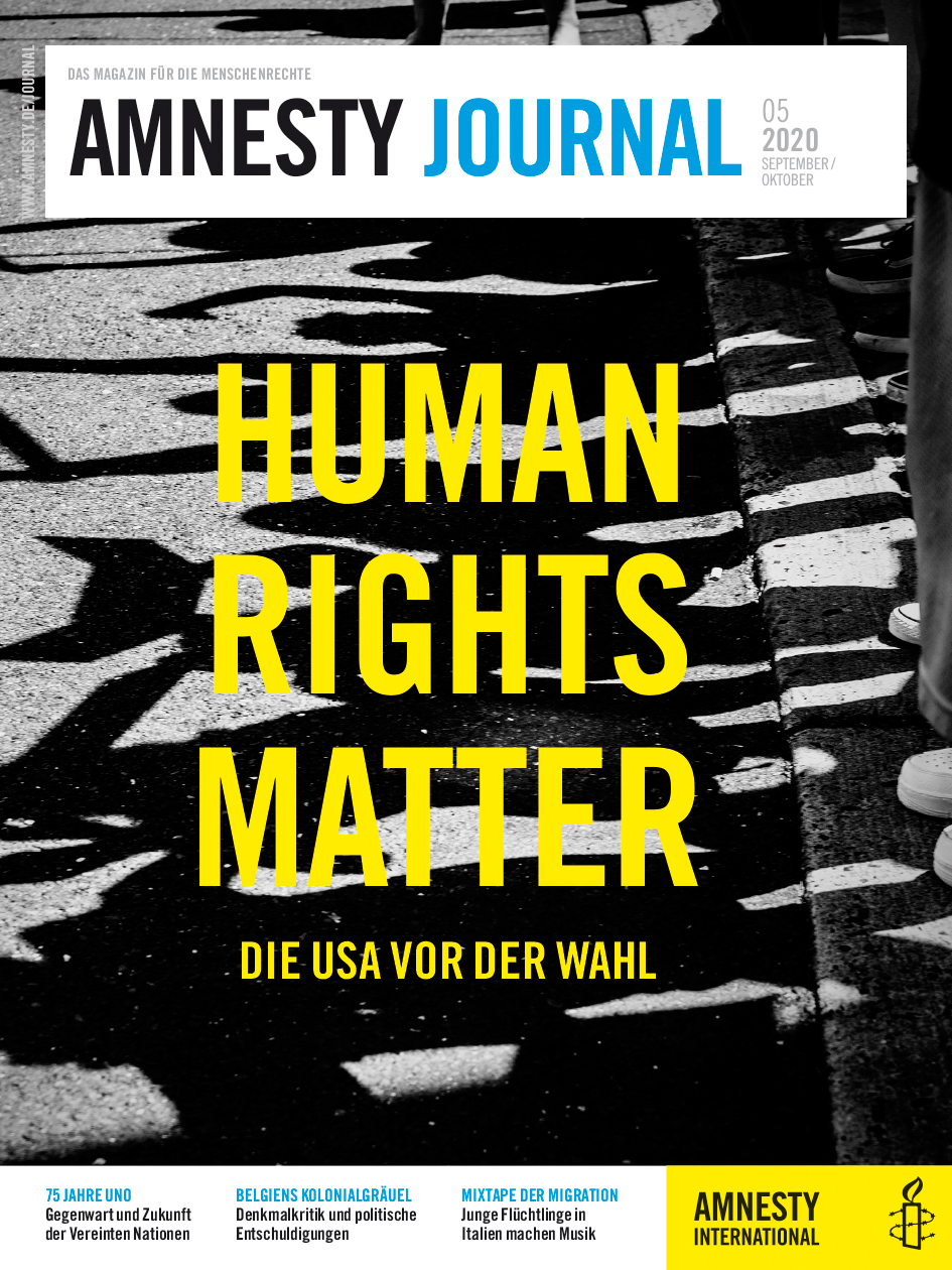 Die Schatten von Demonstrierenden bilden sich auf dem Asphalt einer Straße ab.