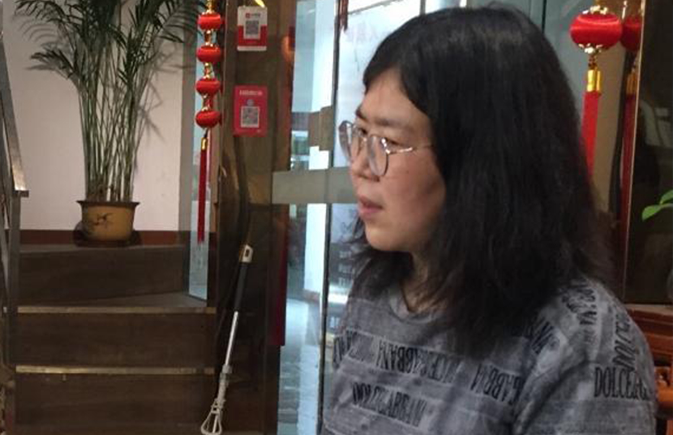  Profilaufnahme einer jungen Frau aus China in dunkler Kleidung.