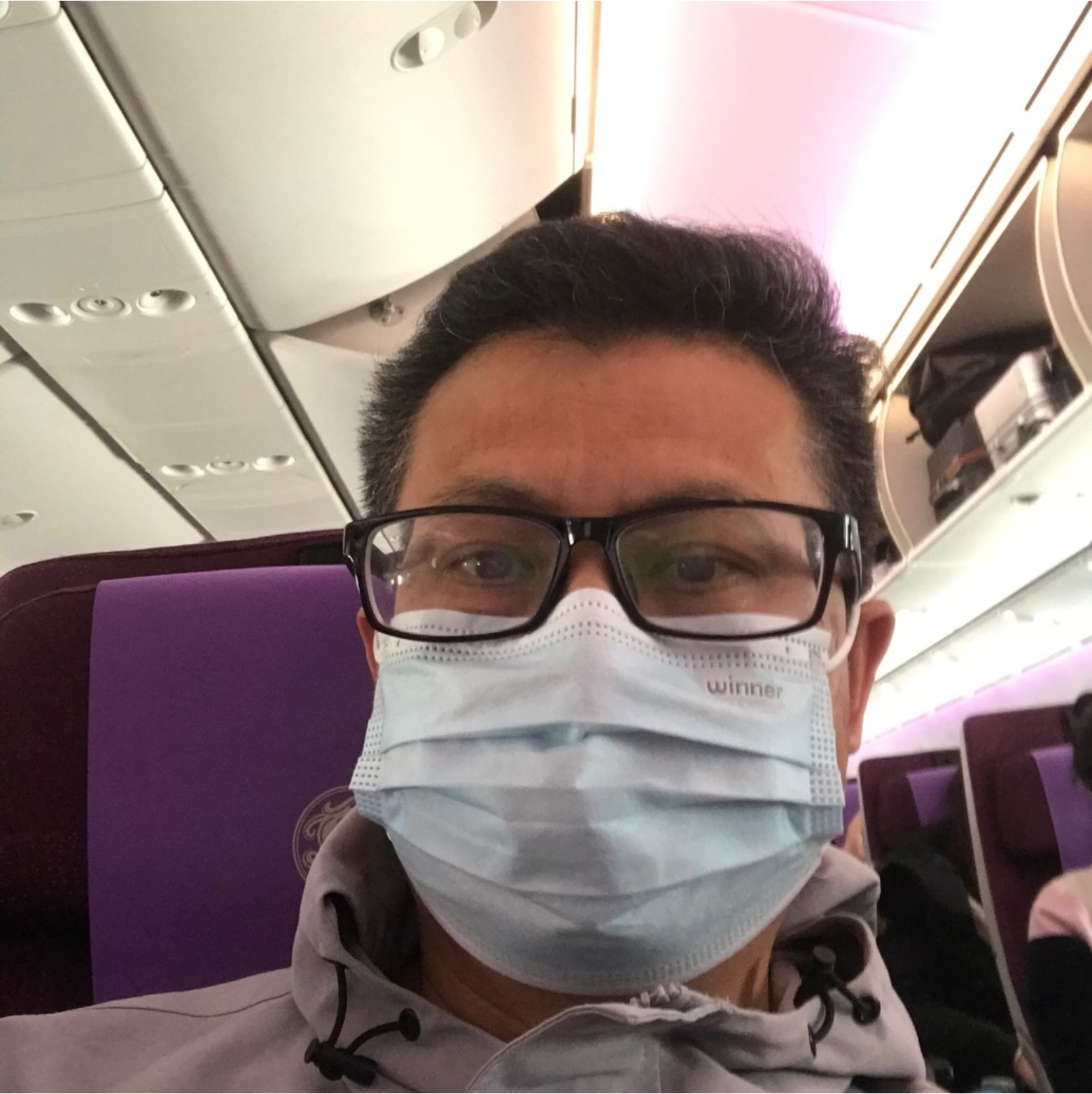 Selfie von Yang Maodong, der auch Guo Feixiong bekannt ist. Er trägt eine Brille und einen Mund-Nase-Schutz. Das Foto wurde auf einem Sitzplatz in einem Flugzeug, Bus oder Zug aufgenommen.
