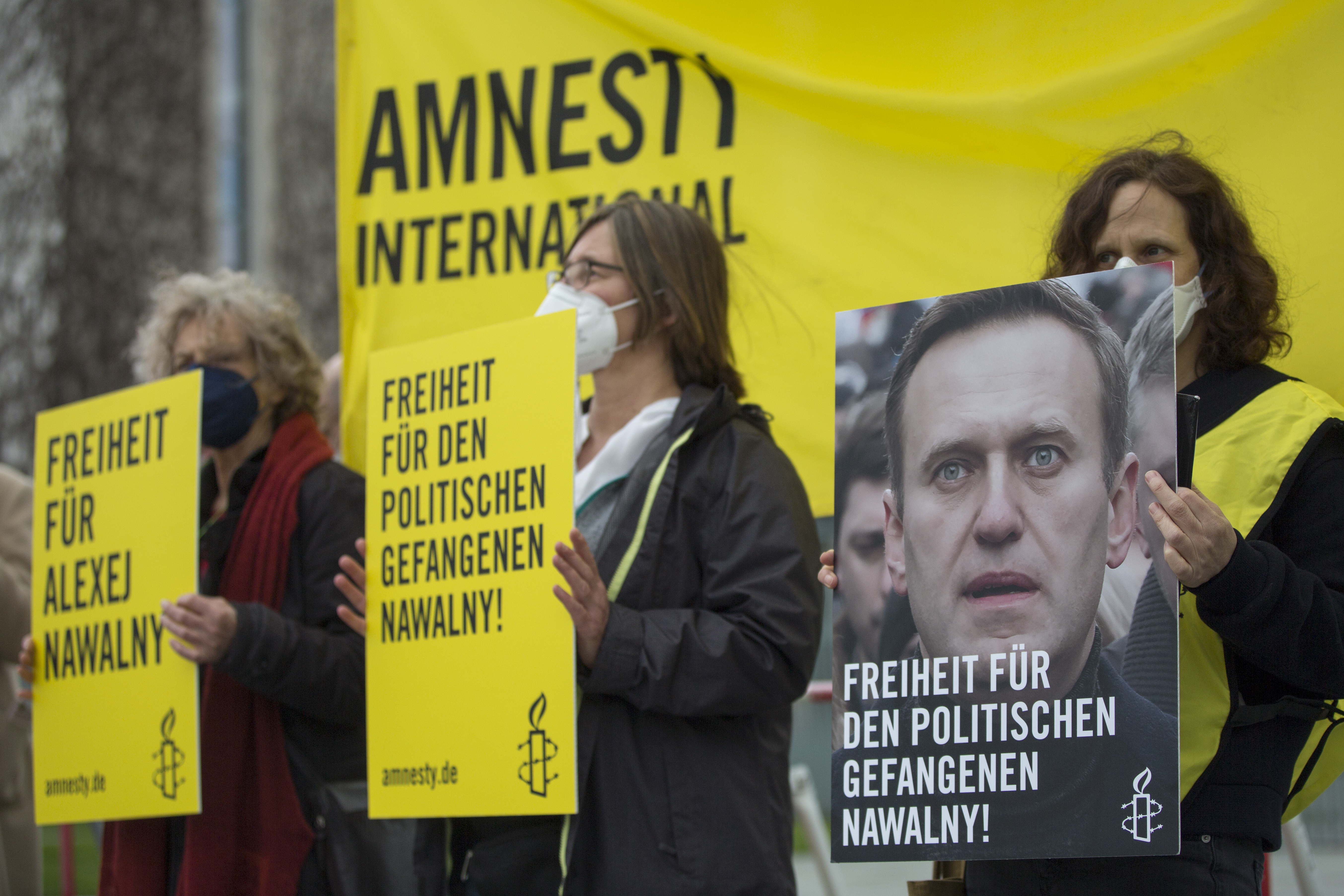 Menschen mit Plakaten, eines zeigt das Porträt von Alexej Nawalny