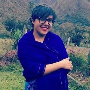 Eine junge Frau trägt eine blaue Jacke und eine schwarze Brille.