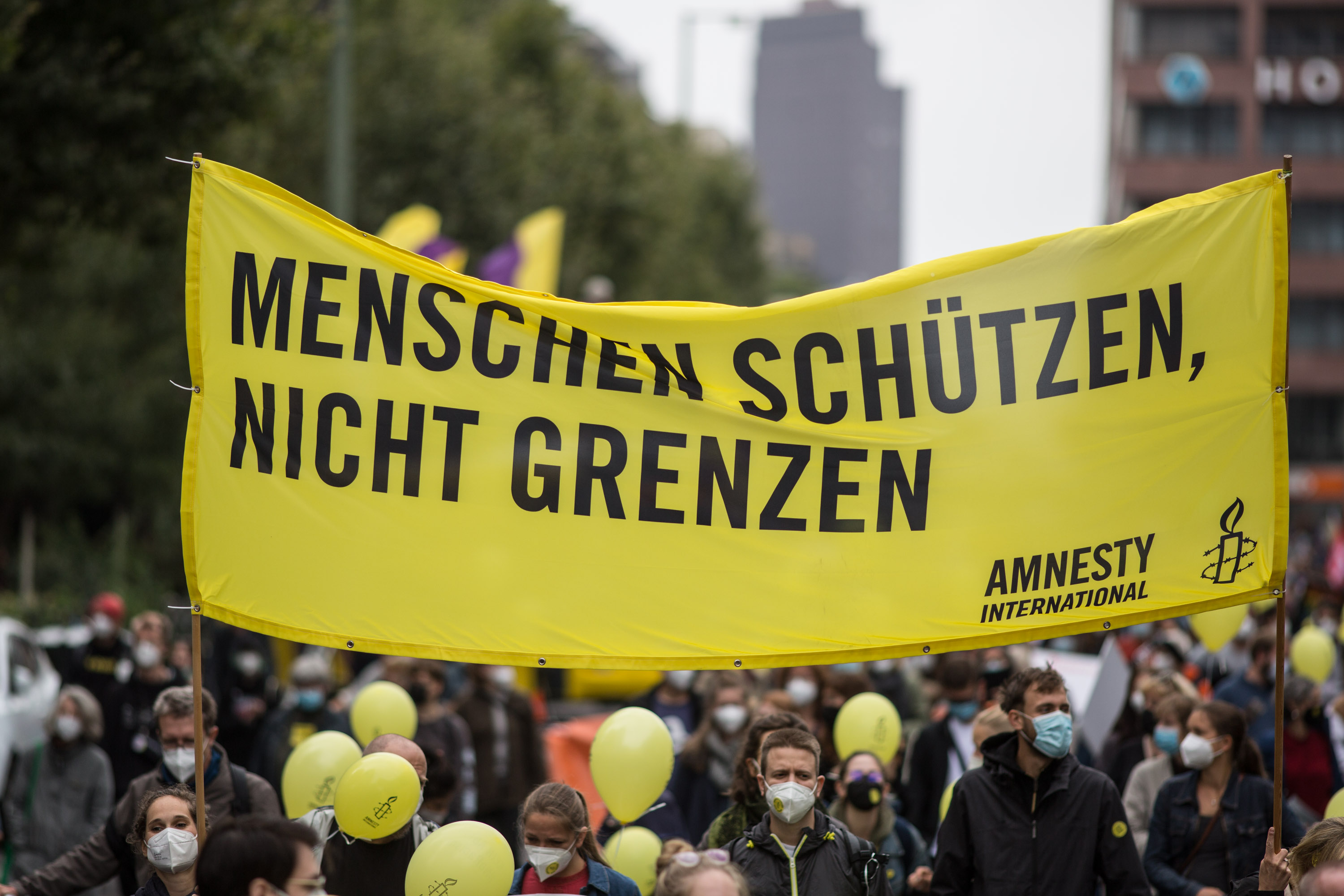 Eine Menschenmenge, auf einem Transparent steht: „Menschen schützen, nicht Grenzen“.