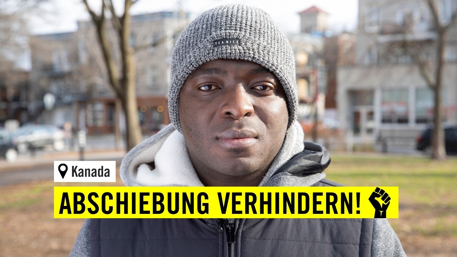 Portraitfoto eines Mannes draussen, er trägt eine graue Mütze und trägt einen grauen Hoodie mit einer schwarzen Veste darüber. Er schaut ernst in die Kamera.