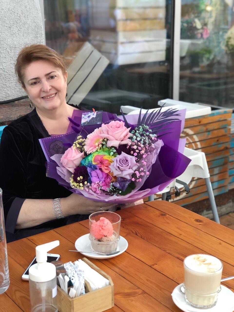 Eine Frau lächelt in die Kamera und hält einen großen Blumenstrauß.