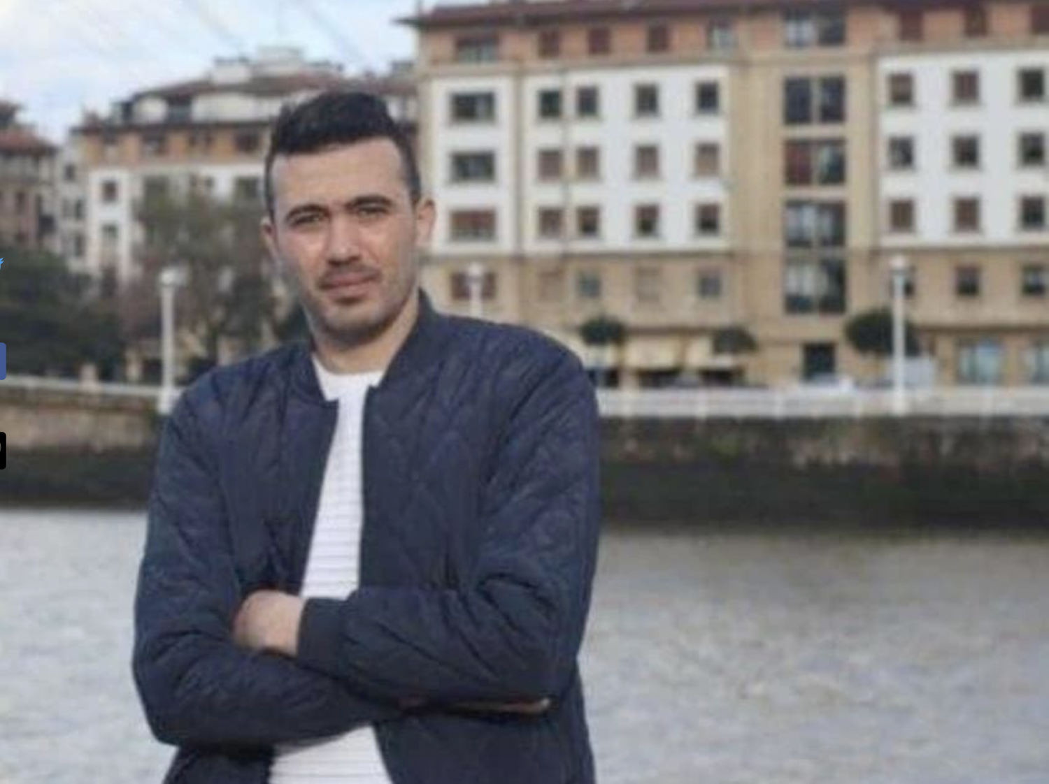 Aufnaheme von Mohamed Benhlima, der in einem Hafen am Rande eines Piers sitzt und mit vor der Brust verschrenkten Armen in die Kamera blickt.