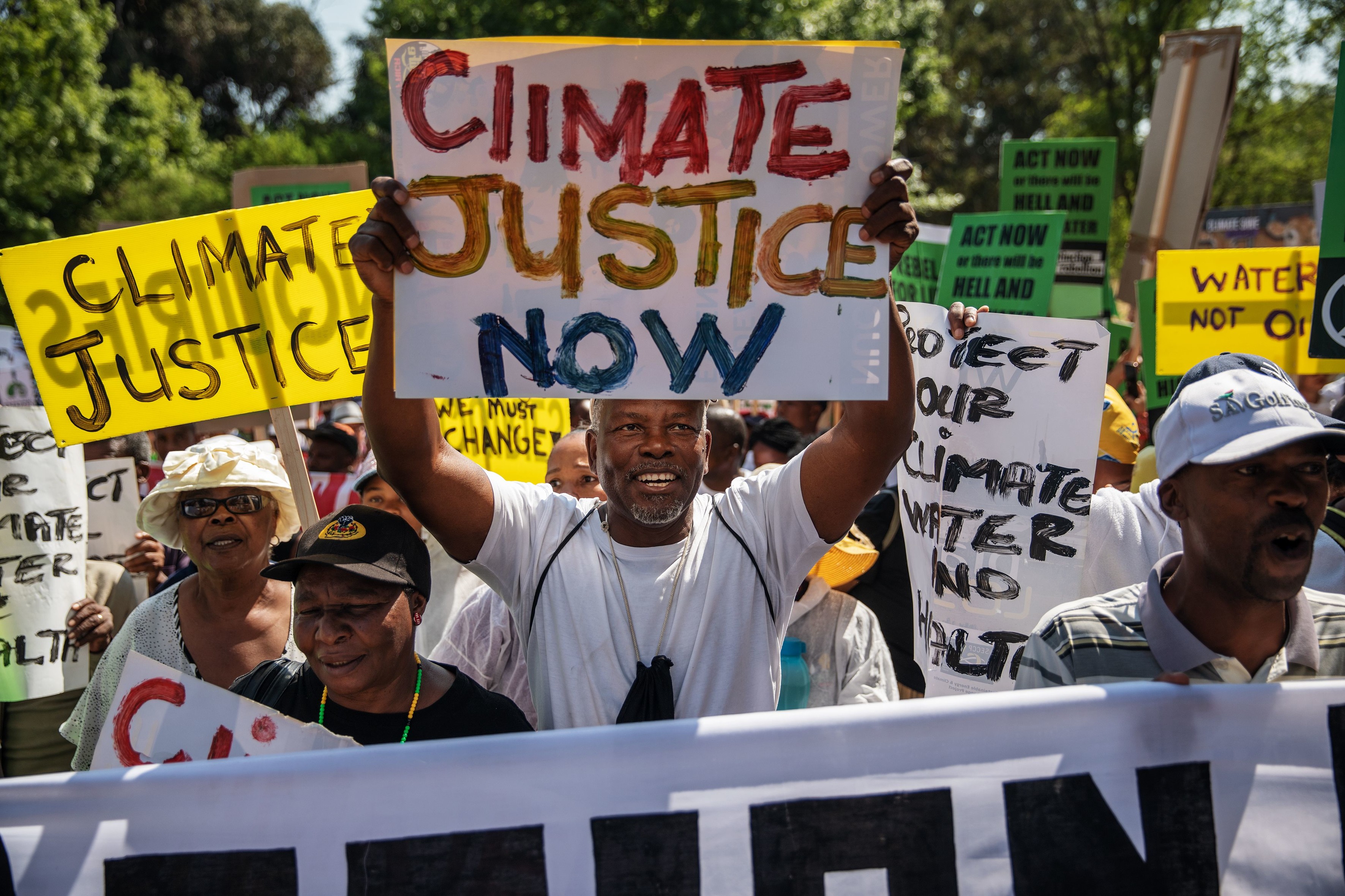 Eine Menschenmenge, in der viele Plakate hochhalten, auf denen die Menschen "Climate justice now", also "Klimagerechtigkeit jetzt" fordern. 