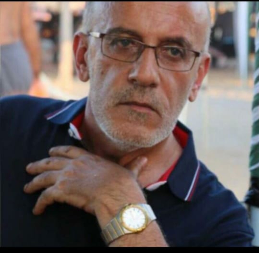 Aufnahme von Ali Maziad, der eine Brille trägt und seine linke Hand auf seine Brust legt.