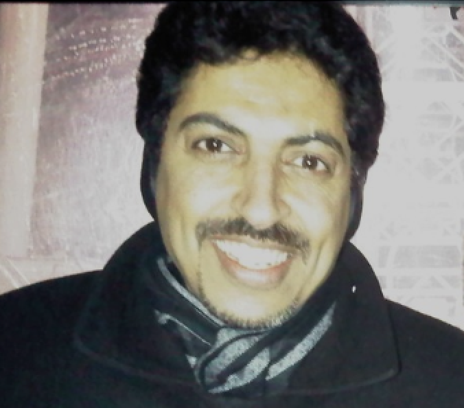 Porträtfoto von Abdulhadi Al-Khawaja, der eine Jacke und ein Schal trägt und die Kamera lächelt.