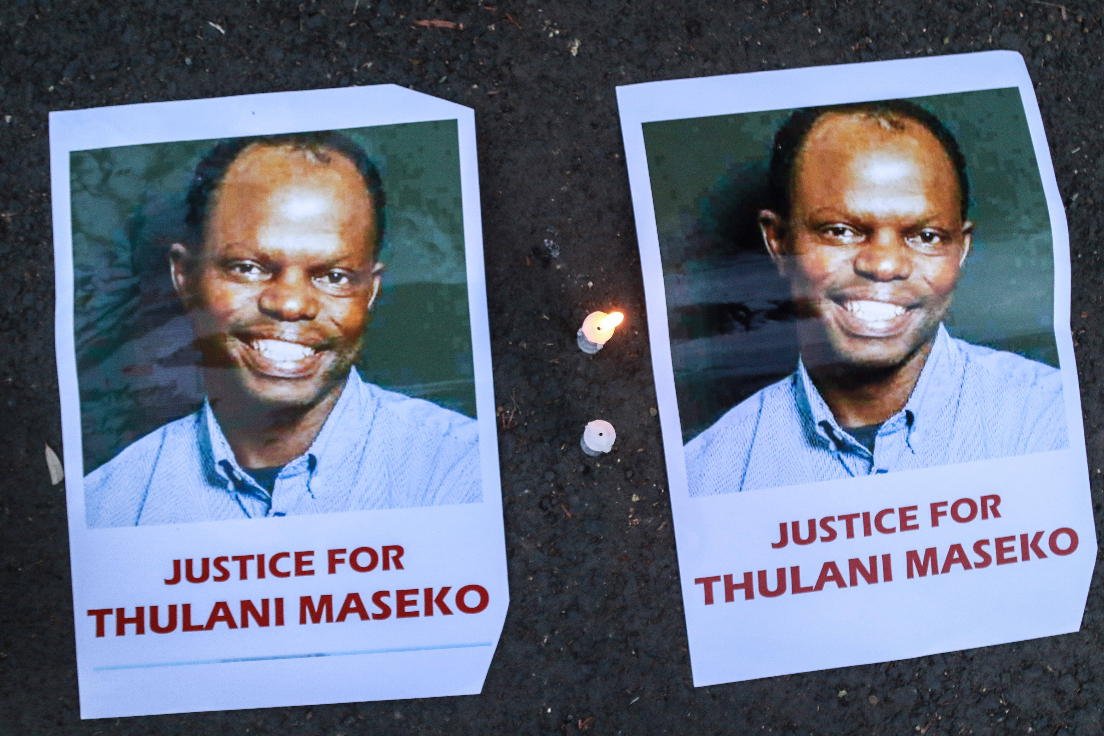 Das Bild zeigt Plakate mit den Porträtfotos eines Mannes, darunter steht "Justice for Thulani Maseko"