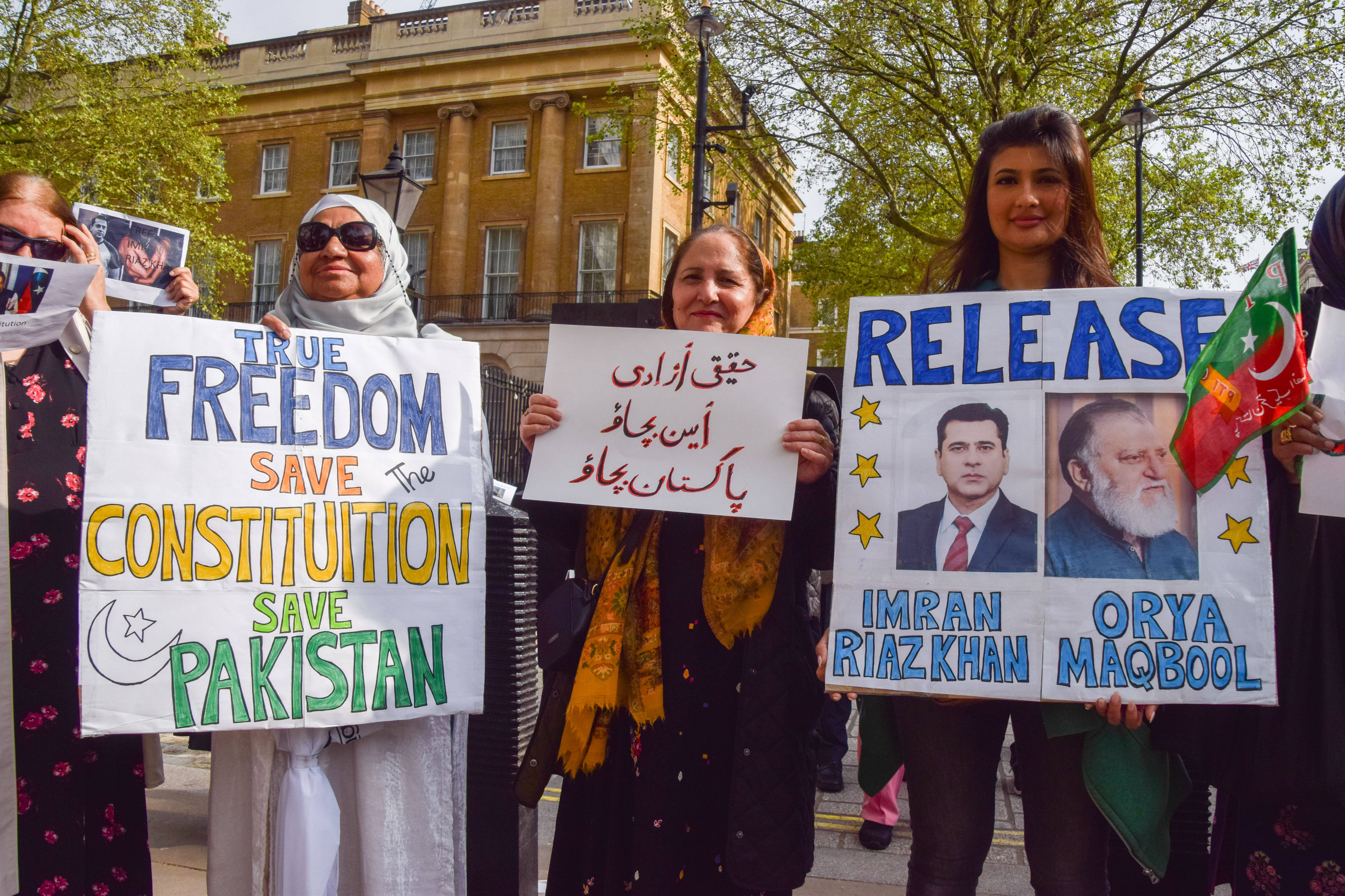 Mehrere Personen stehen vor einem Gebäude und halten Plakate hoch. Auf einem steht: "Release Imran Riaz Khan".