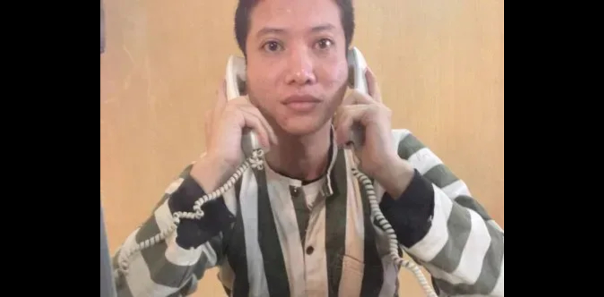 Ein Mann in einem schwarz-weiß-gestreiften Anzug hält sich an beide Ohren je ein Kabeltelefon. Es ist Nguyễn Văn Chưởng. 