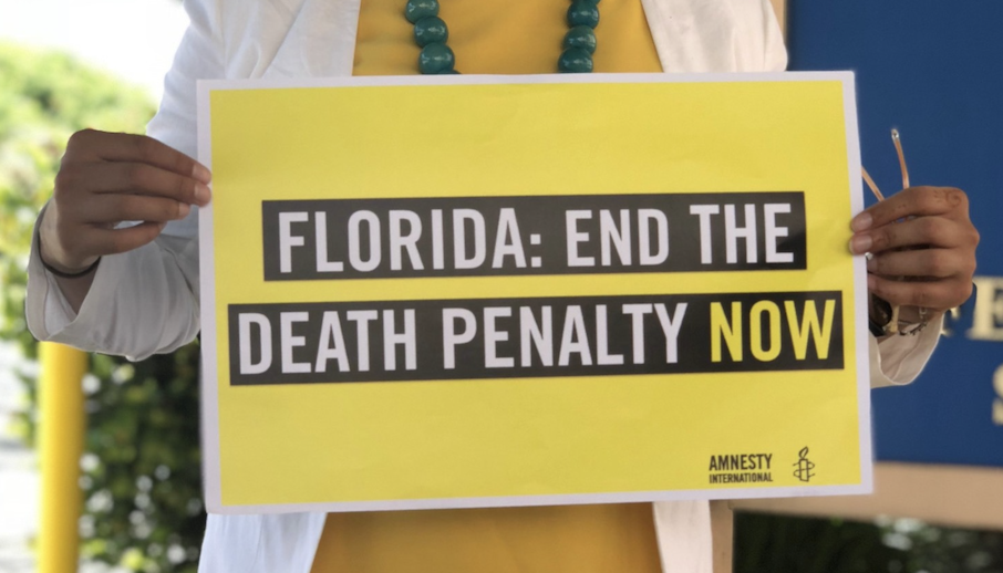 Eine Frau hält ein Plakat vor sich, auf dem steht "Florida: Ende the Deathy Penalty now!"