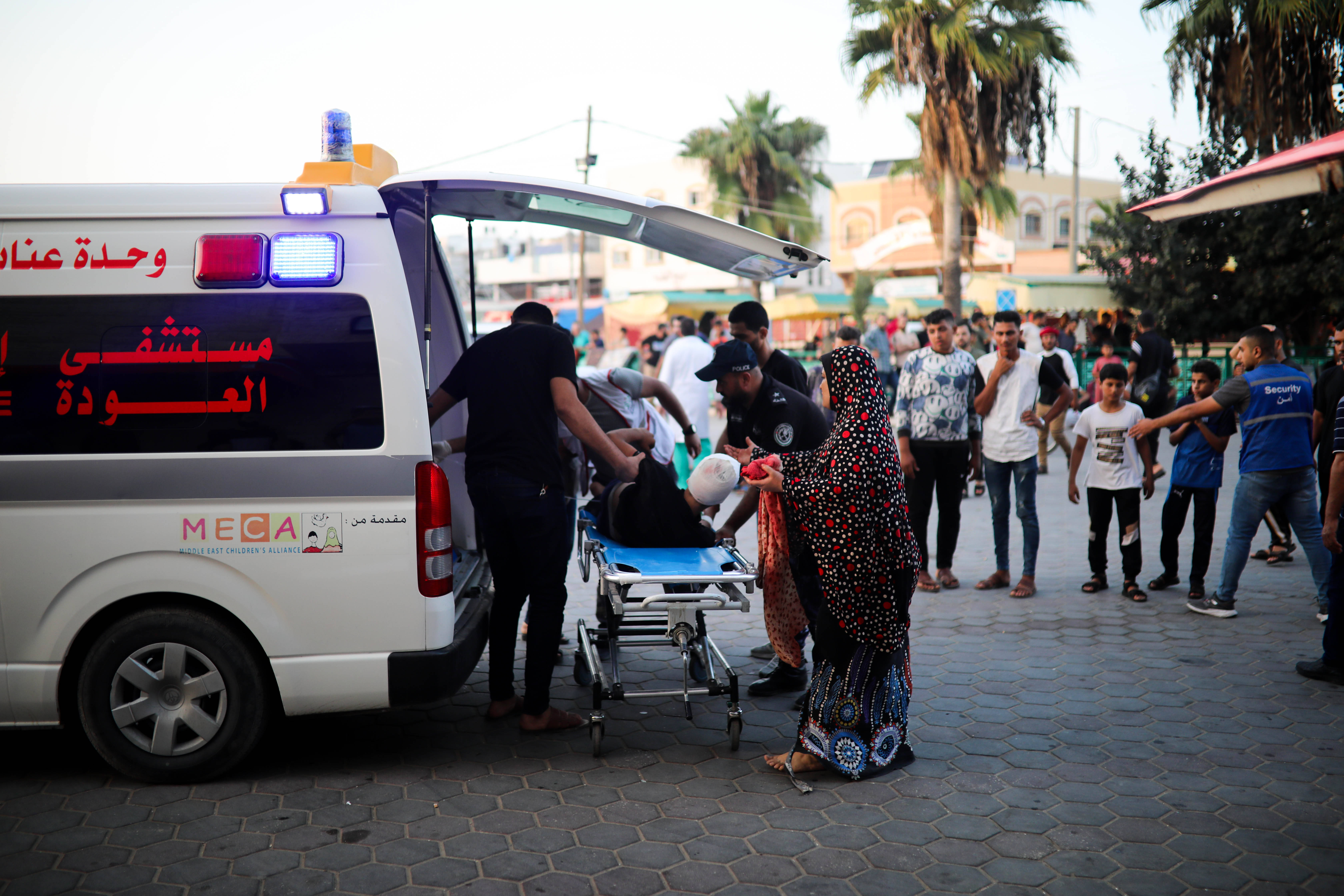 Das Bild zeigt einen Krankenwagen und viele Menschen darum