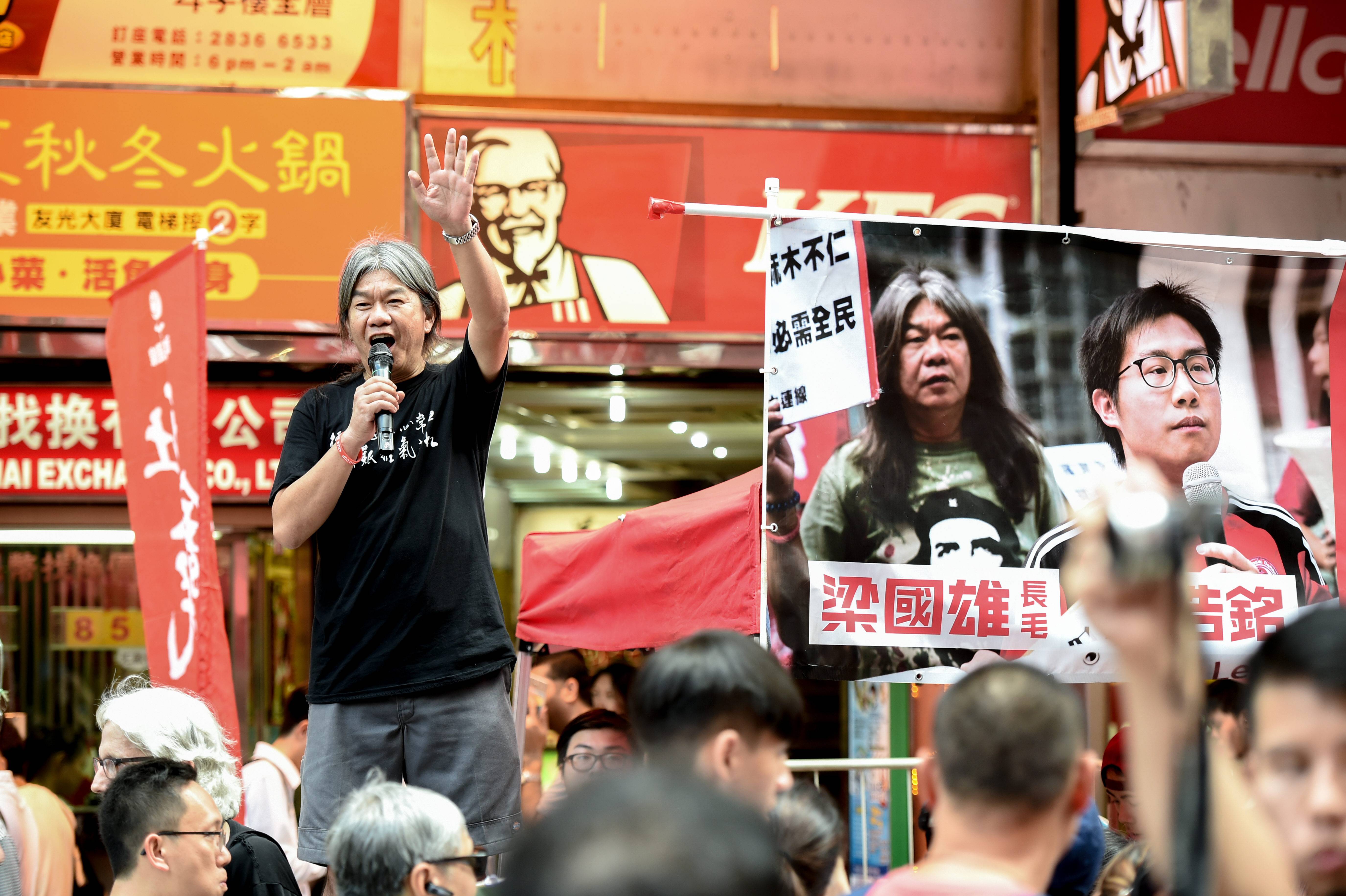 Das Foto zeigt Leung Kwok-hung, der bei einer Demonstration mit einem Mikrofon in der rechten Hand auf einer Bühene steht und zu der Menschenmenge spricht.