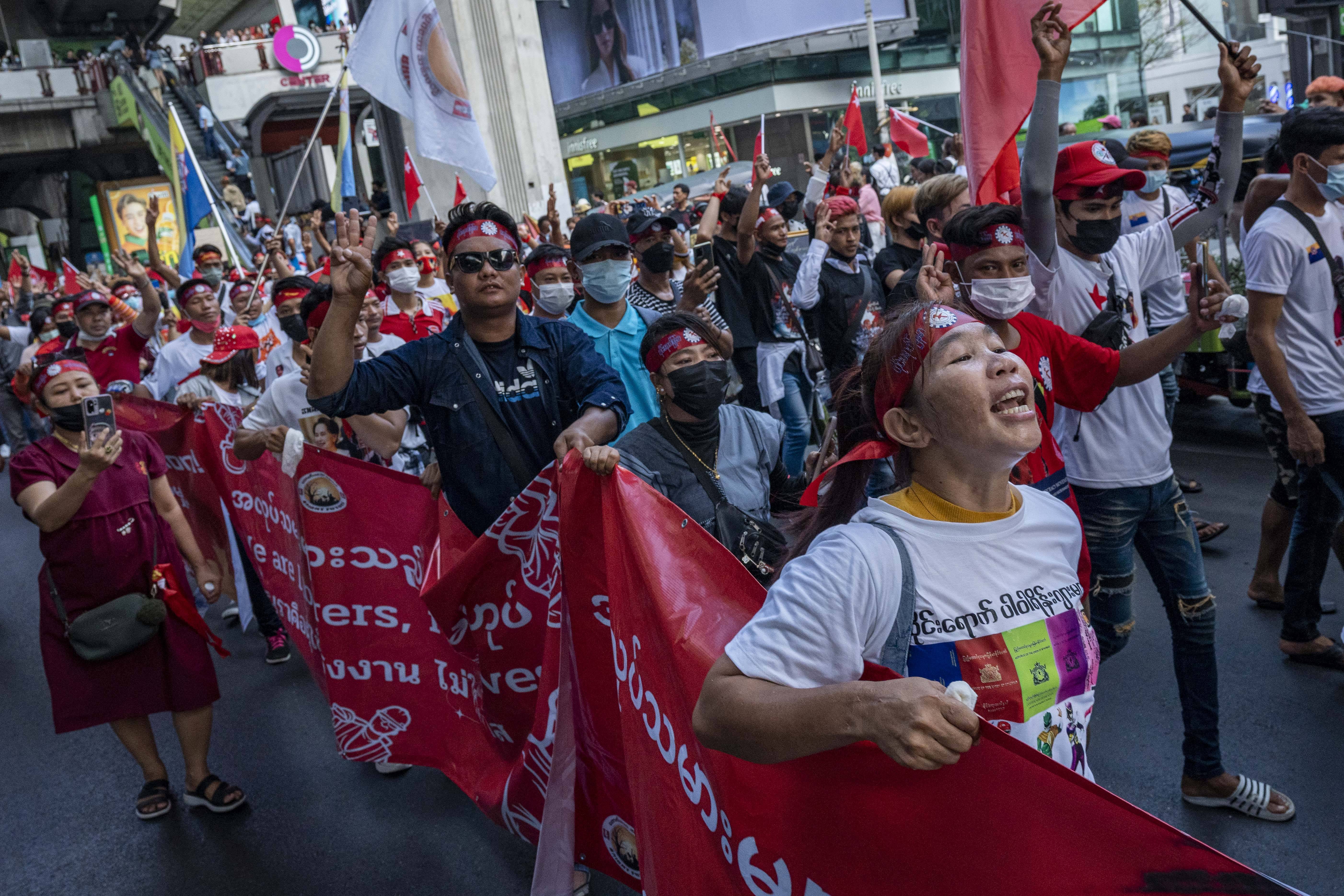 Das Bild zeigt viele Menschen, die protestieren und eine großes rotes Banner in der Hand halten
