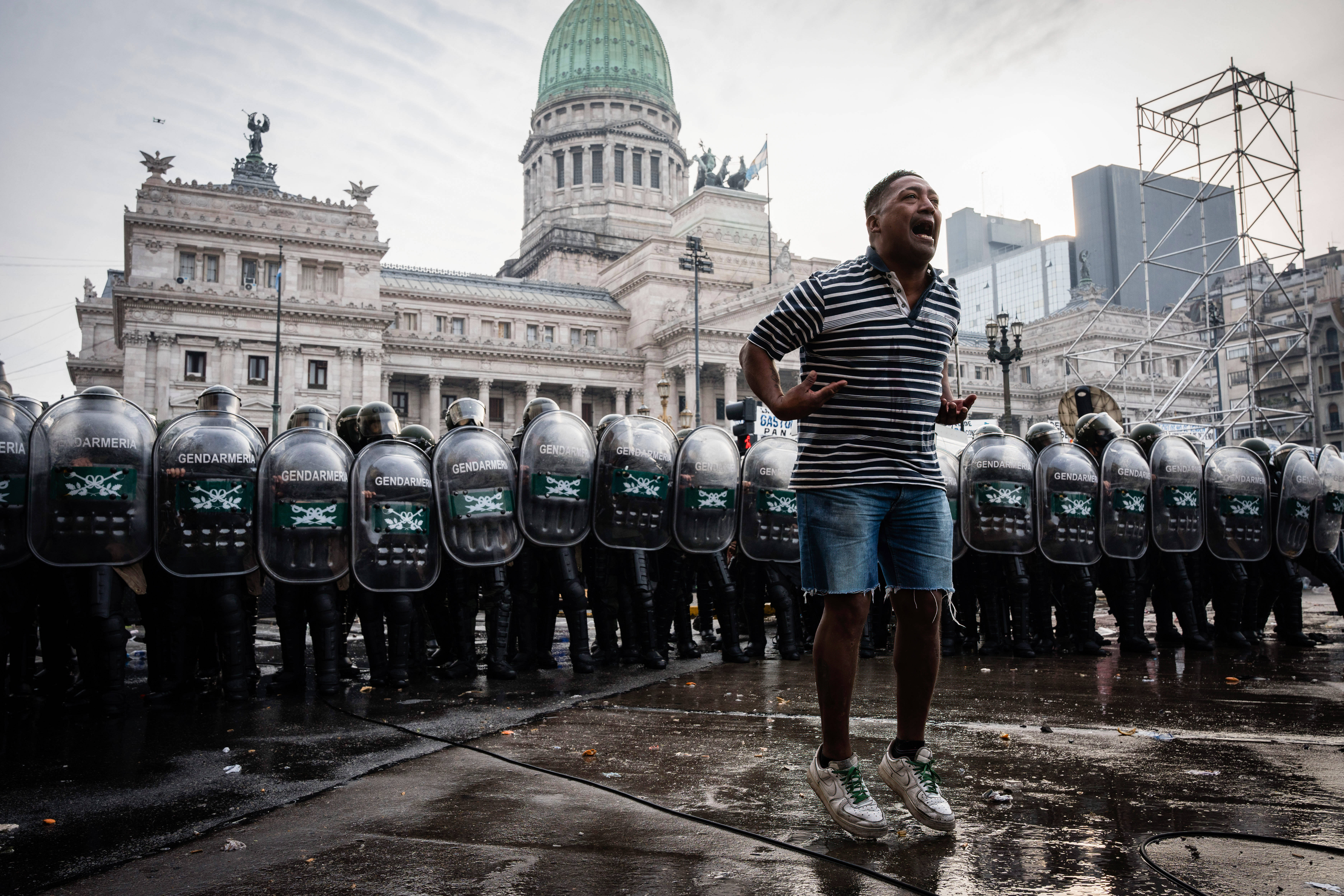 Das Bild zeigt einen Mann, der vor einer Polizei-Kette steht und etwas ruft
