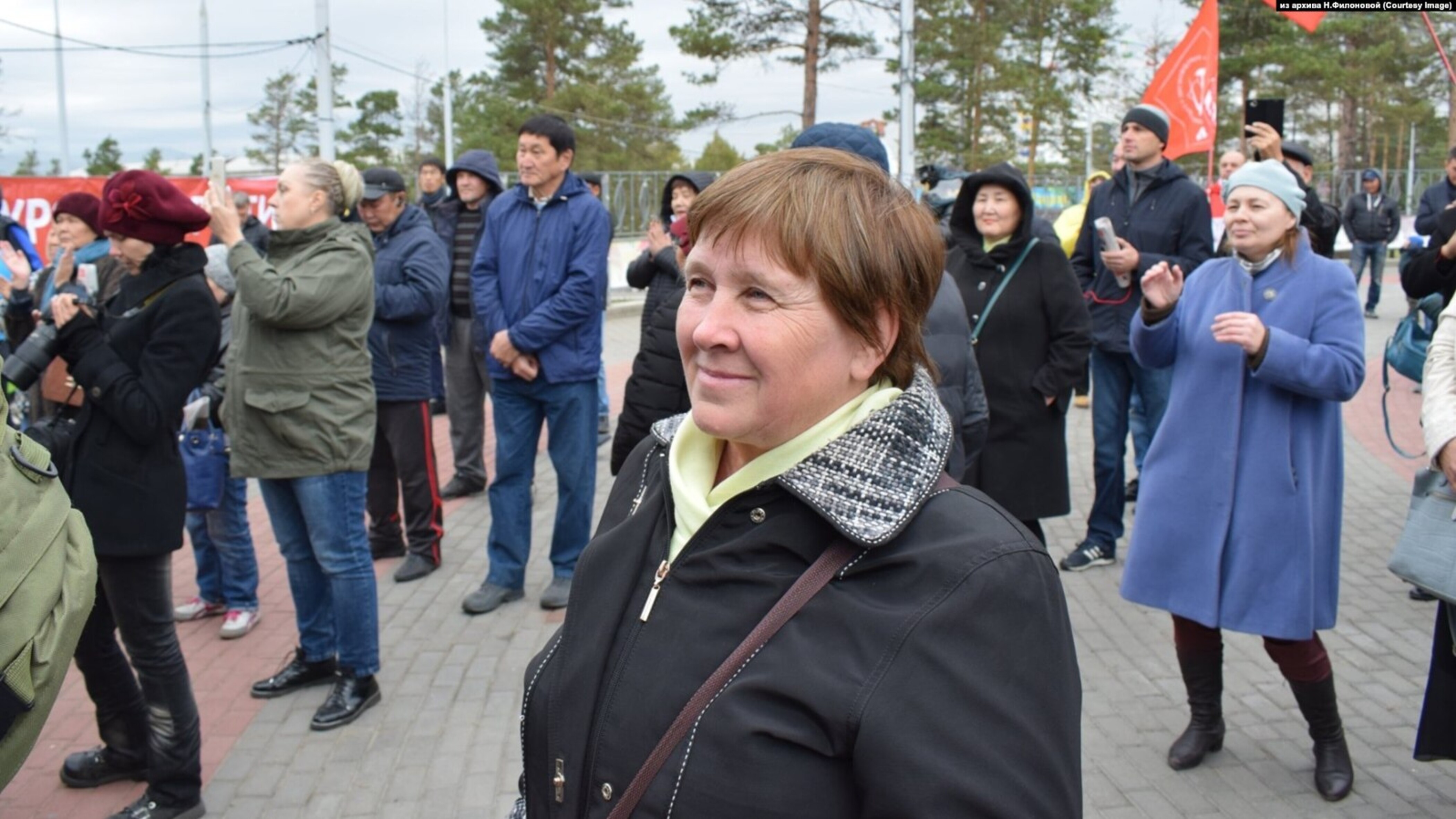 Das Foto zeigt Natalya Filonova lächelnd auf einem Platz stehend. Hinter ihr stehend mehrere Menschen.