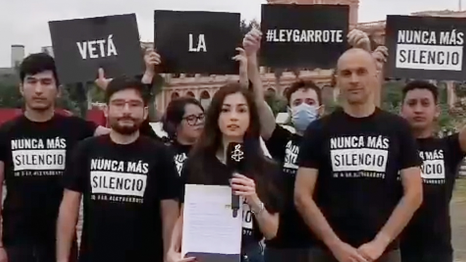 Das Foto zeigt mehrere Personen, die in die Kamera blicken. Einige halten Schilder mit Slogans noch. Alle tragen das gleiche T-Shirt, auf dem steht: "Nunca mas silencio!"