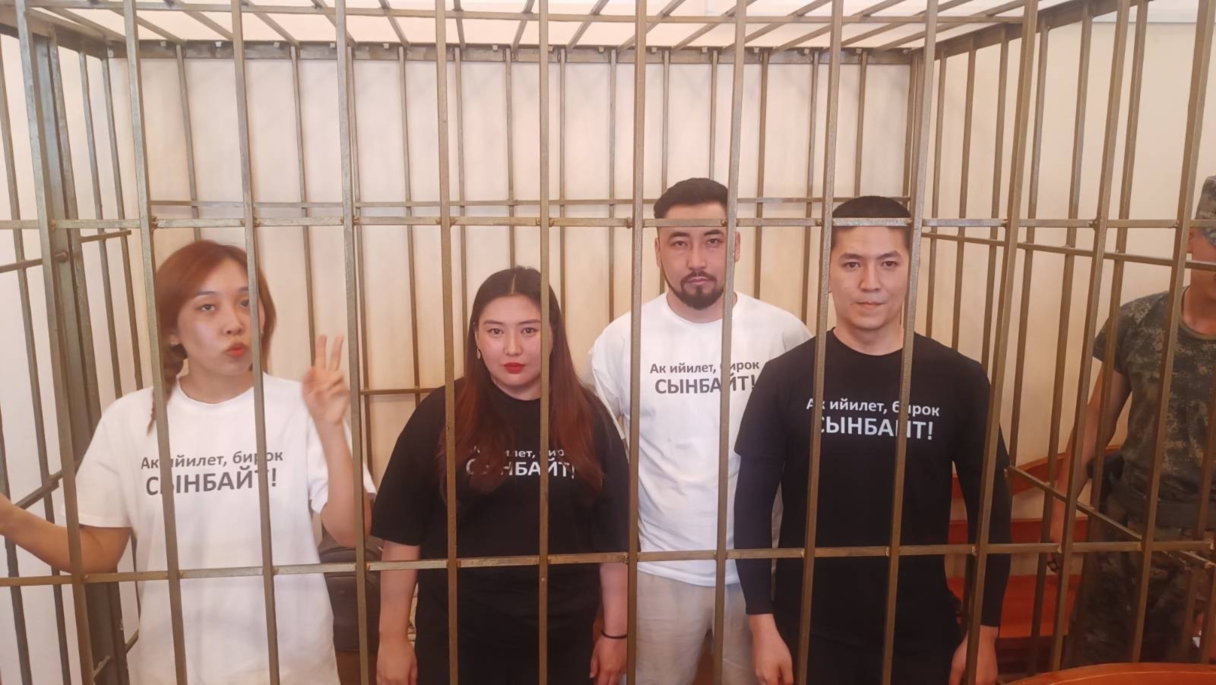 Das Foto zeigt zwei Frauen und zwei Männer hinter Gittern in einem Käfig in einem Gerichtssaal.