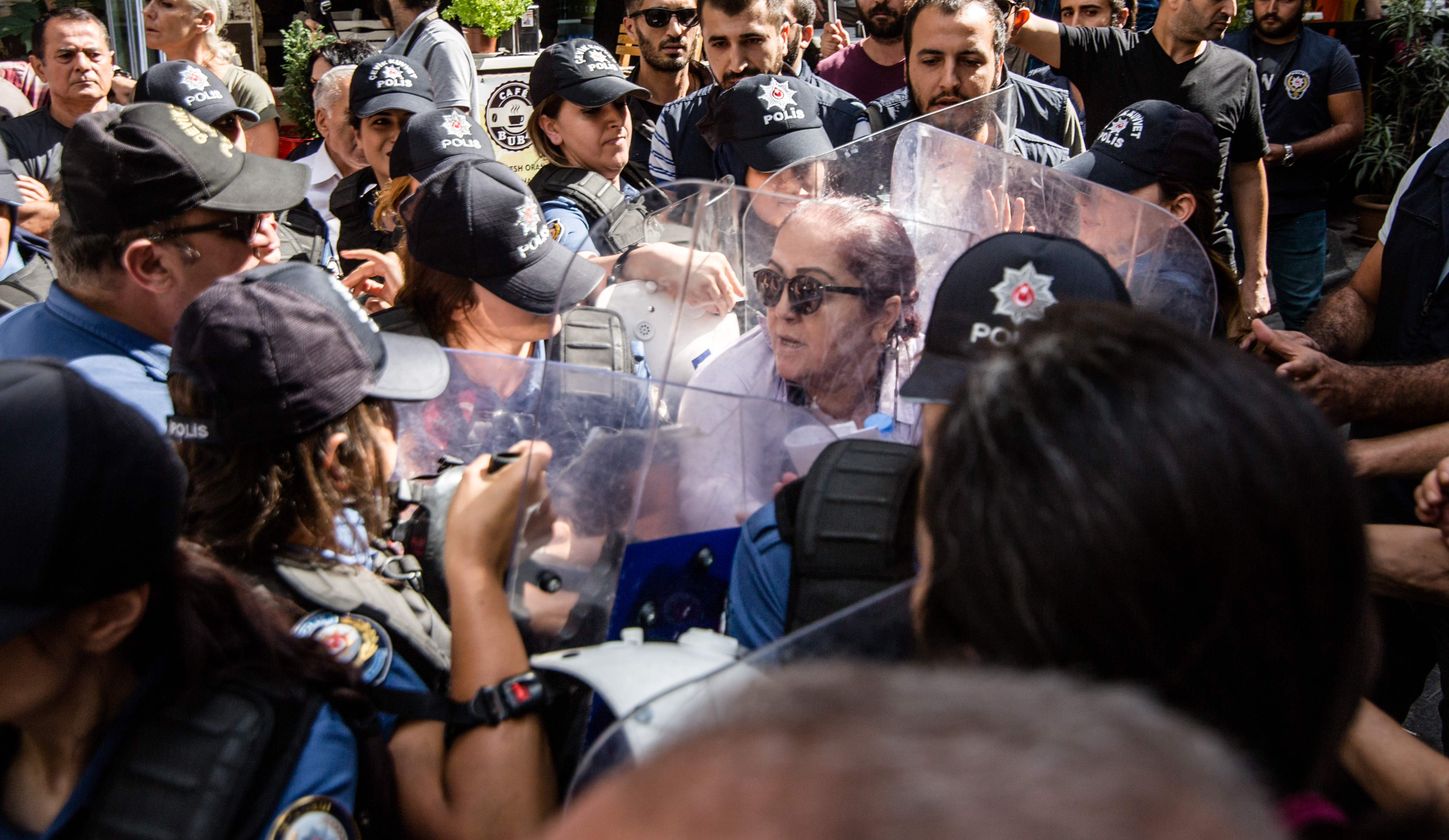 Das Bild zeigt eine Frau, die von Polizisten*innen umringt ist