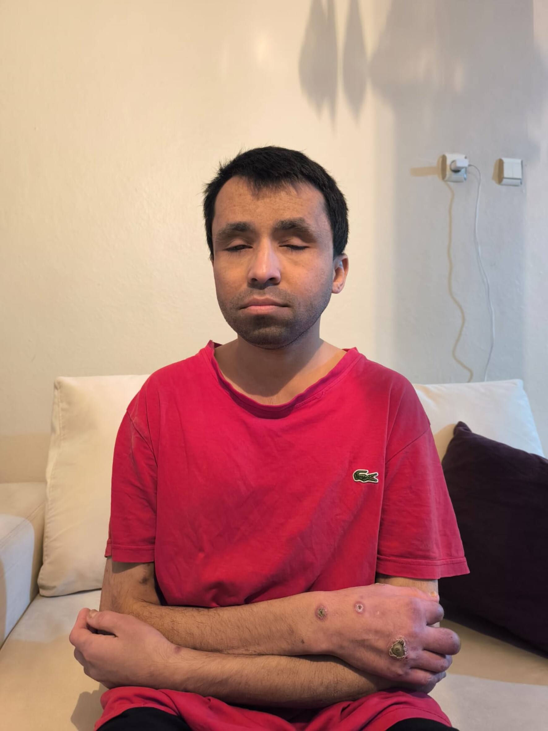 Das Foto zeigt Tabriz Saifi mt geschlossenen Augen und verschränkten Armen auf einem Sofa sitzend.