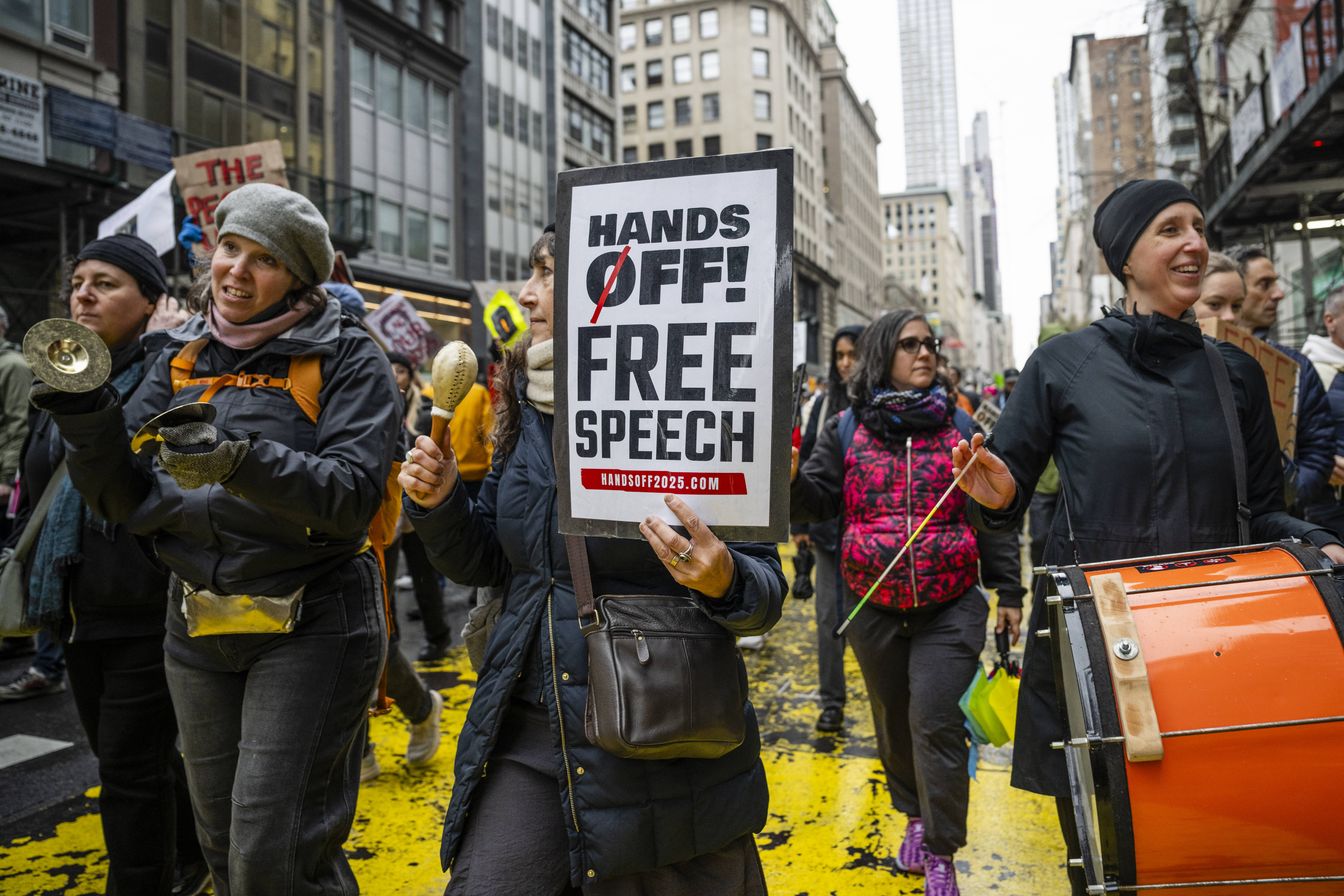 Das Foto zeigt mehrere Frauen in einem Demonstrationszug auf einer Straße. Eine von ihnen hält ein Plakat hoch, auf dem steht: "Hands off! Free speech".