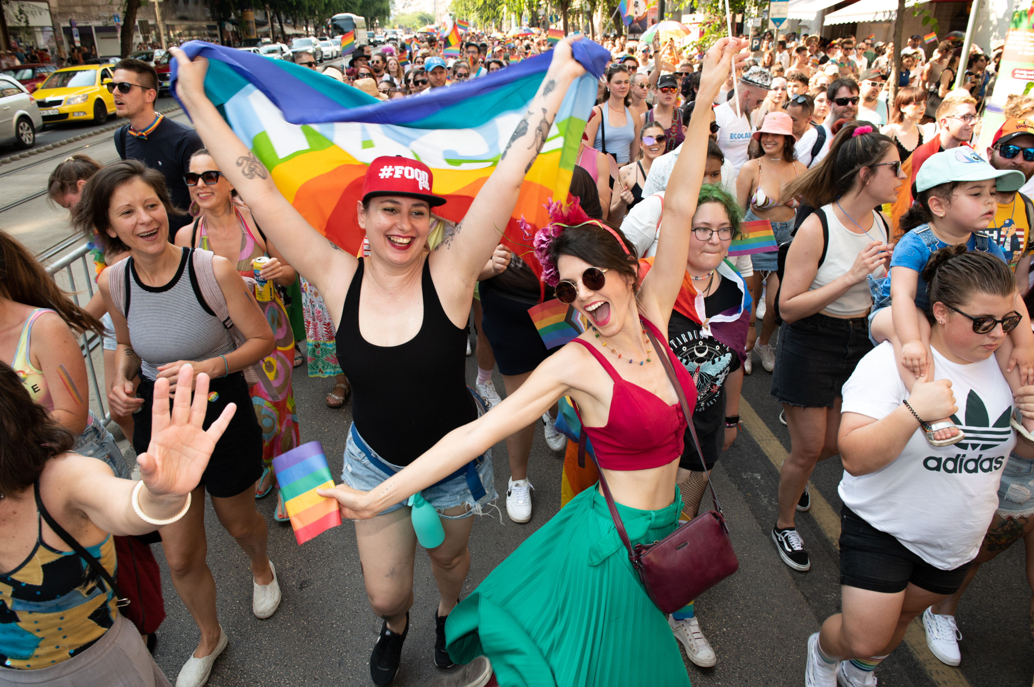 Demonstrierende halten eine Regenbogenfahne hoch.
