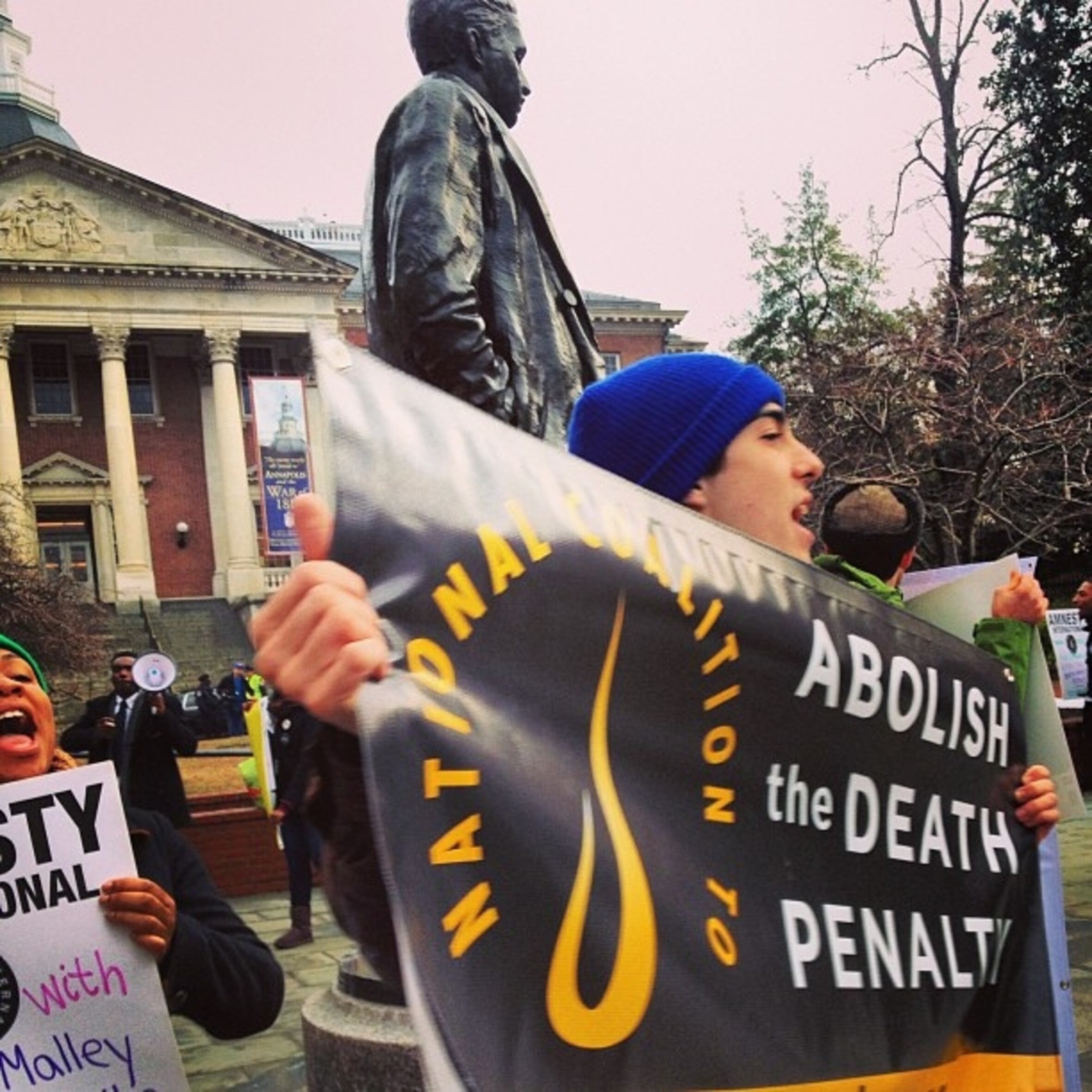 Das Foto zeigt einen jungen Mann, der ein Banner mit Amnesty-Logo vor sich hält. Auf dem Banner steht: "Abolish the death penalty".
