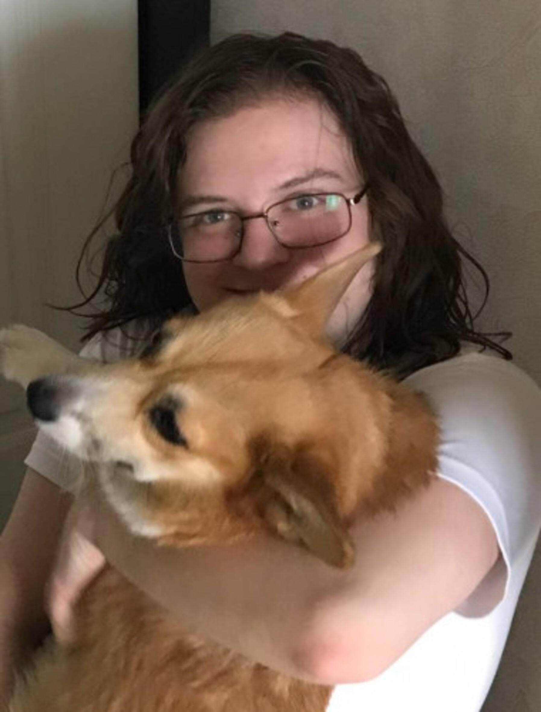 Das Foto zeigt Mark Kislitsyn in die Kamera lächelnd, während er einen Hund in seinen Armen hält. Er trägt eine Brille und hat längere Haare.