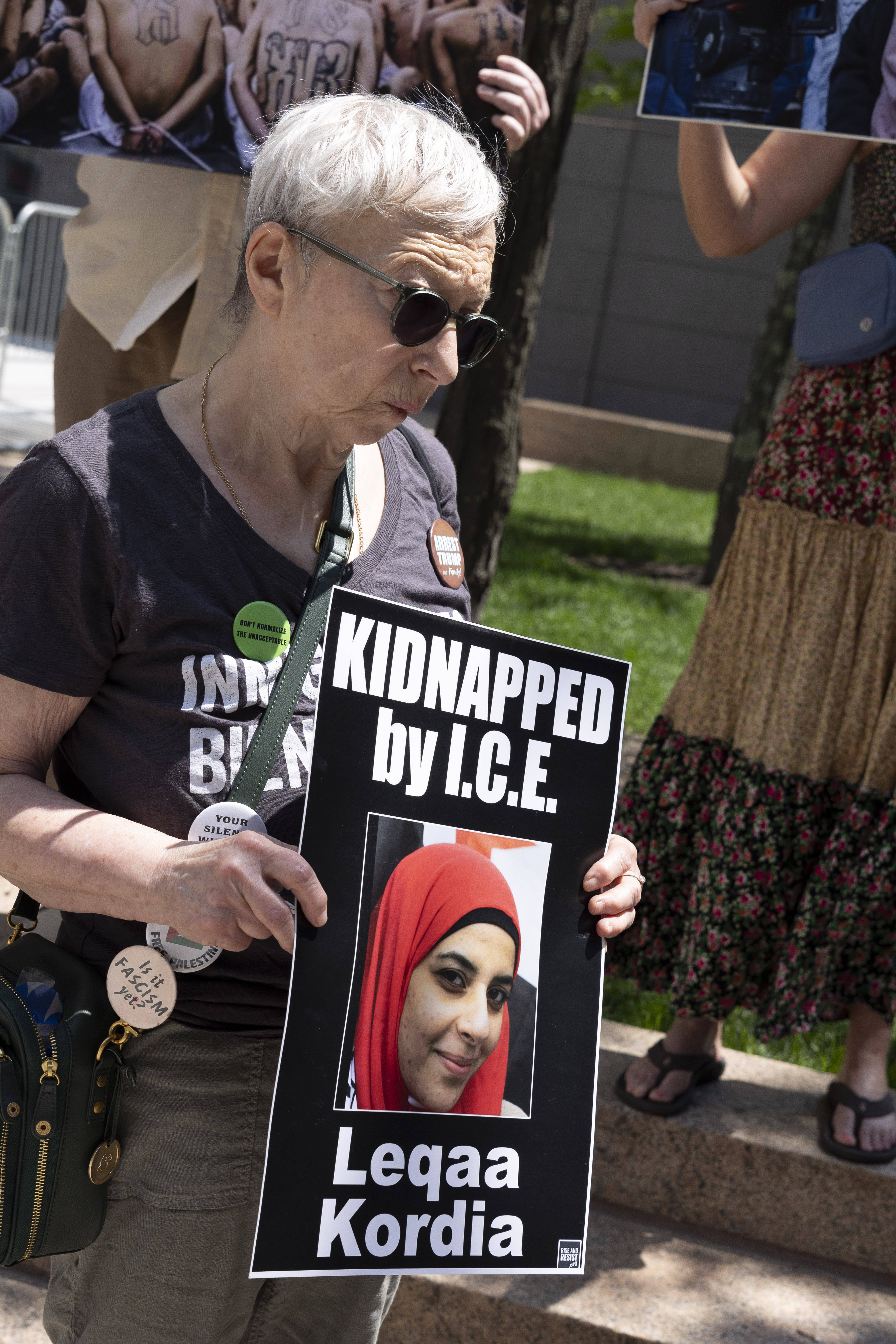 Das Foto zeigt eine Demonstrantin, die ein Pappschild in der Hand hält mit dem Foto von Leqaa Kordia, die auf dem Bild ein Kopftuch trägt.