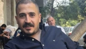 Porträtfoto von Said Abdelrazek, mutmaßlich aufgenommen im Außenbereich eines Cafés. Er trägt ein Hemd, dessen obere Knöpfe offen sind. Er lächelt in die Kamera.