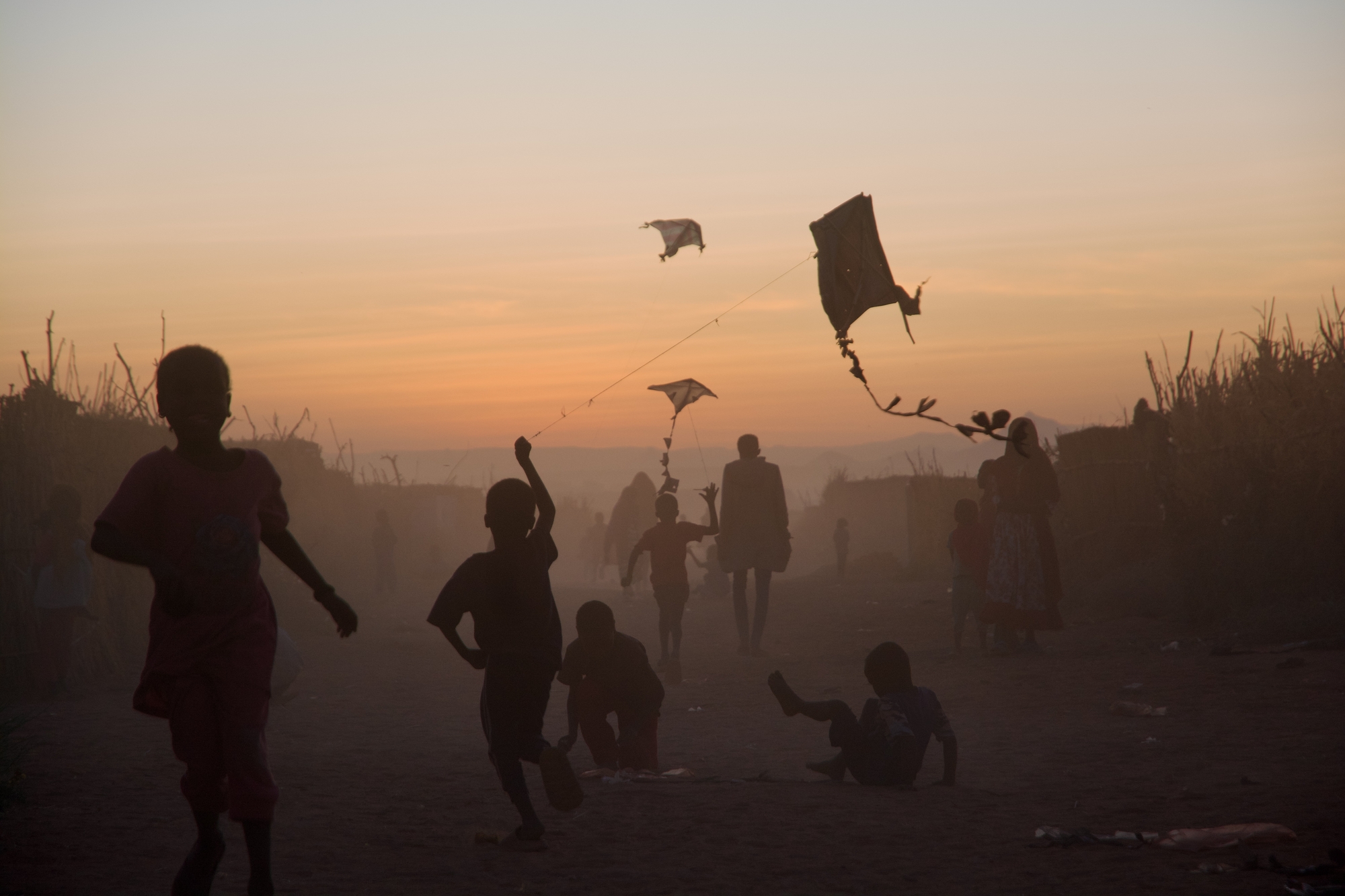 Kinder spielen mit Drachen im Sonnenuntergang